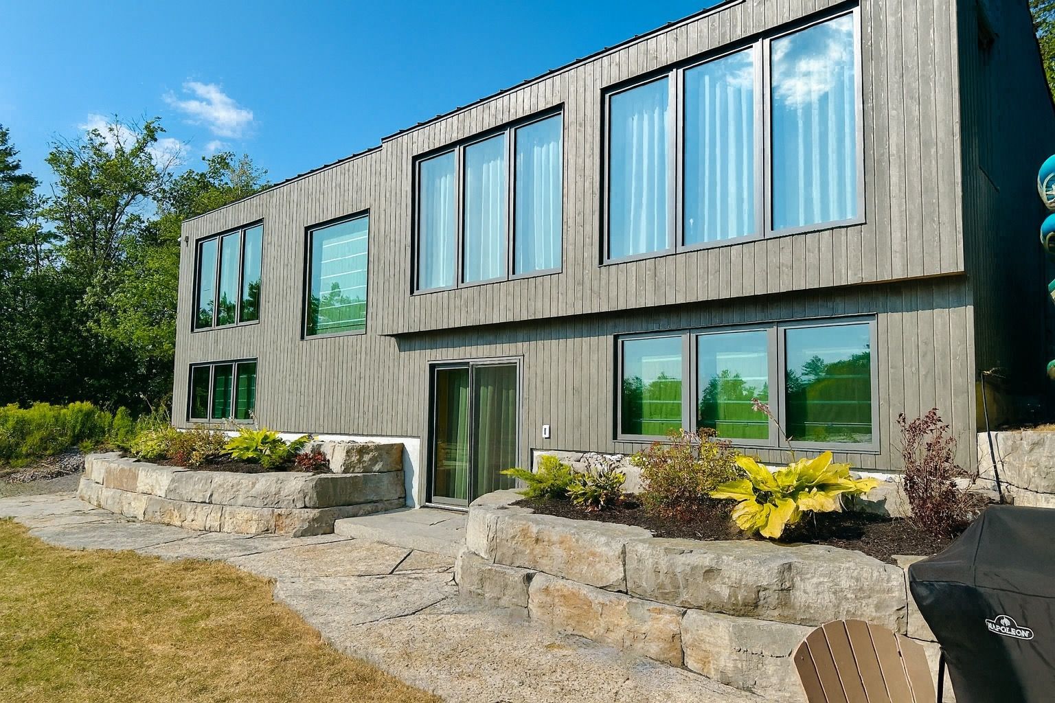 image Striking contemporary exterior with large windows capturing sweeping lake and sunset views.