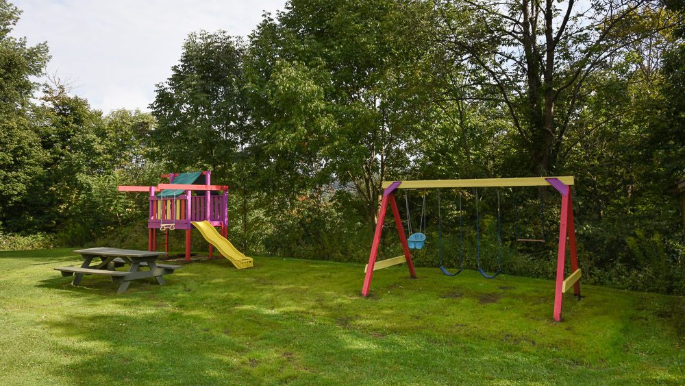 image Open green space with swings and picnic area where little ones can play and families can unwind.