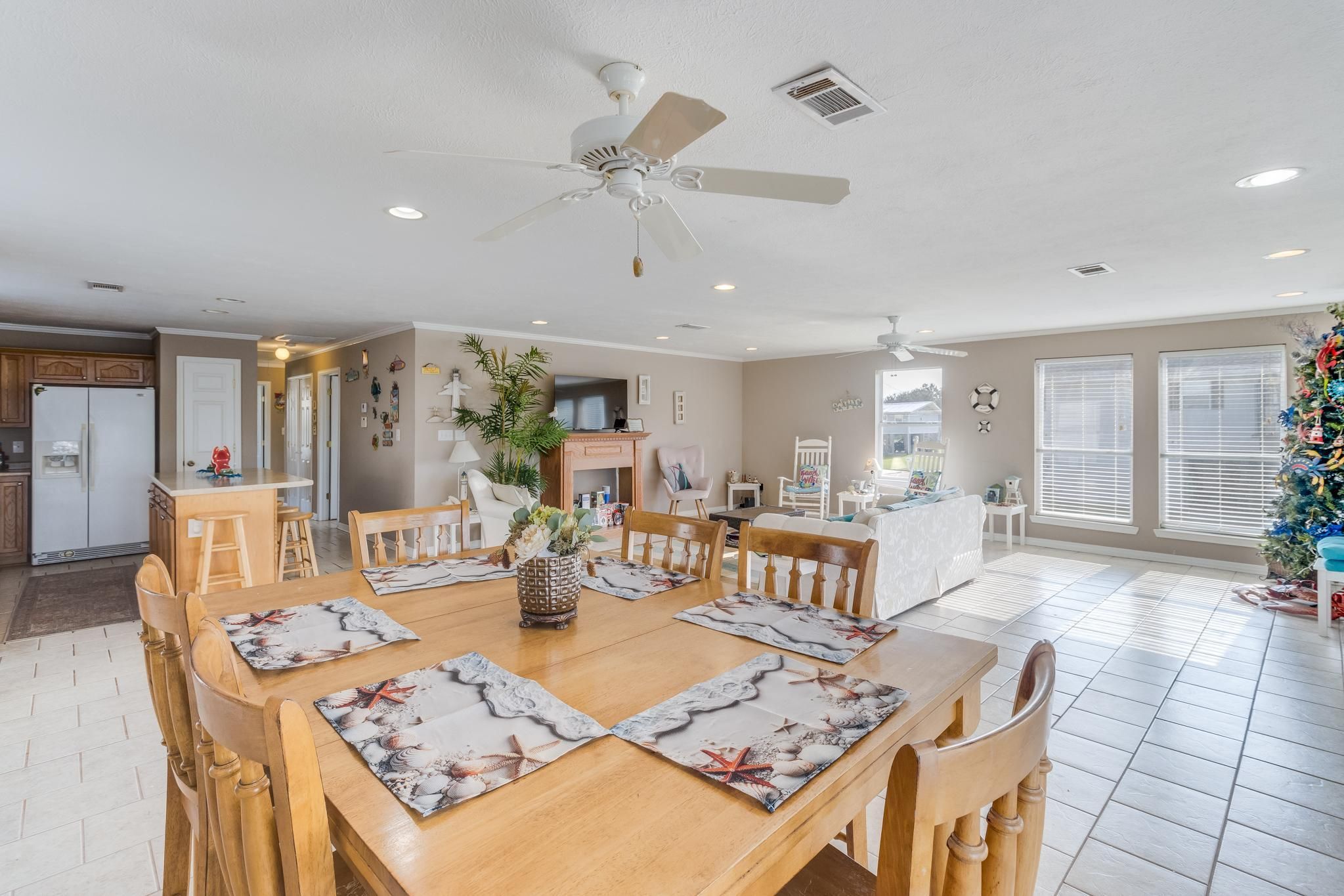 image The open dining area seamlessly connects to the bright living room, featuring a warm wooden table and beach-themed decor.