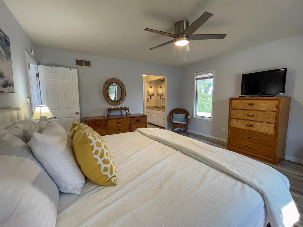 image Spacious bedroom with king bed, dresser, and ceiling fan for comfort.