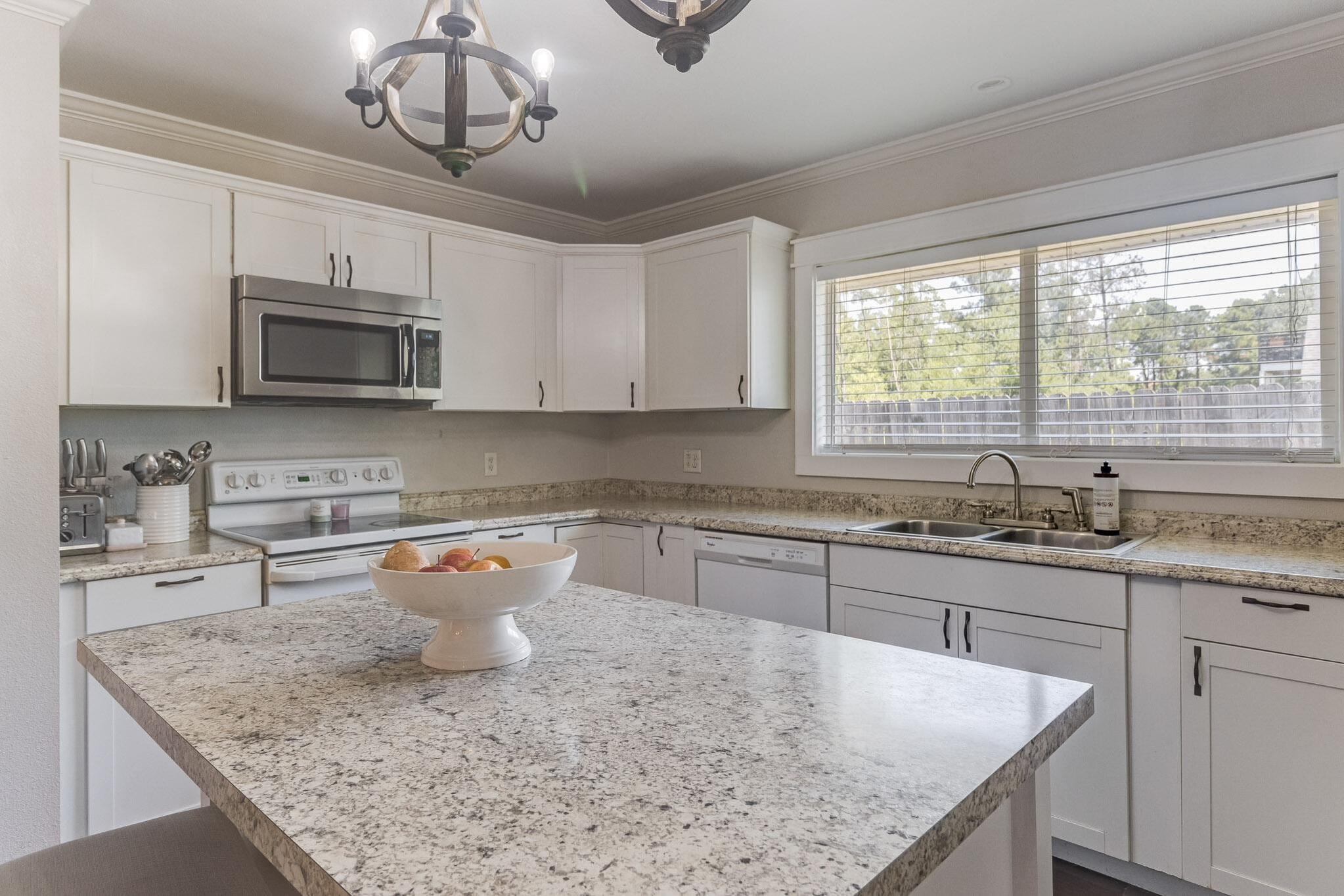 image Modern kitchen with granite countertops, stainless steel appliances, and a sunny windowed sink.