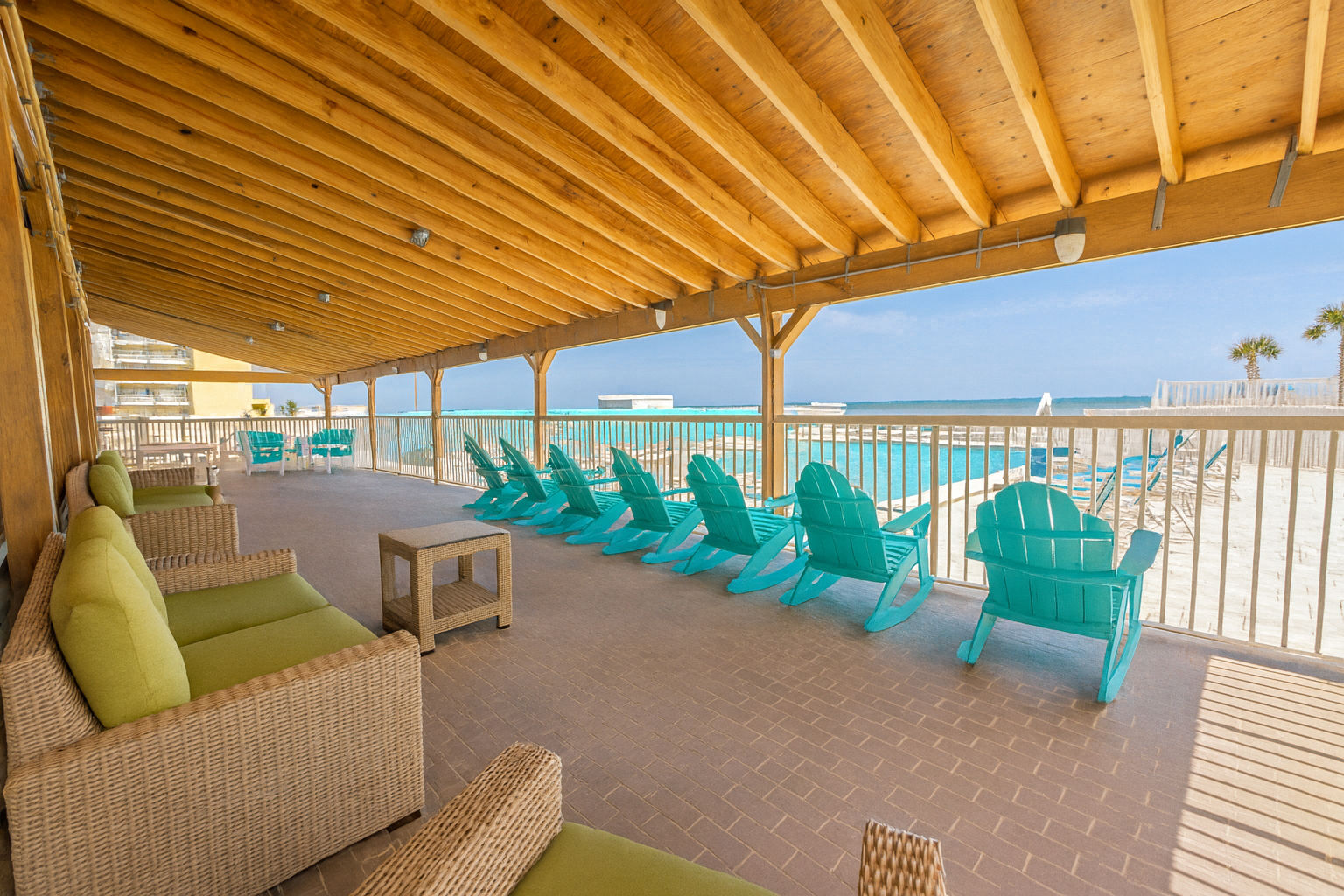 image Unwind in the shaded lounge area overlooking the beach, complete with colorful chairs that enhance your coastal getaway.
