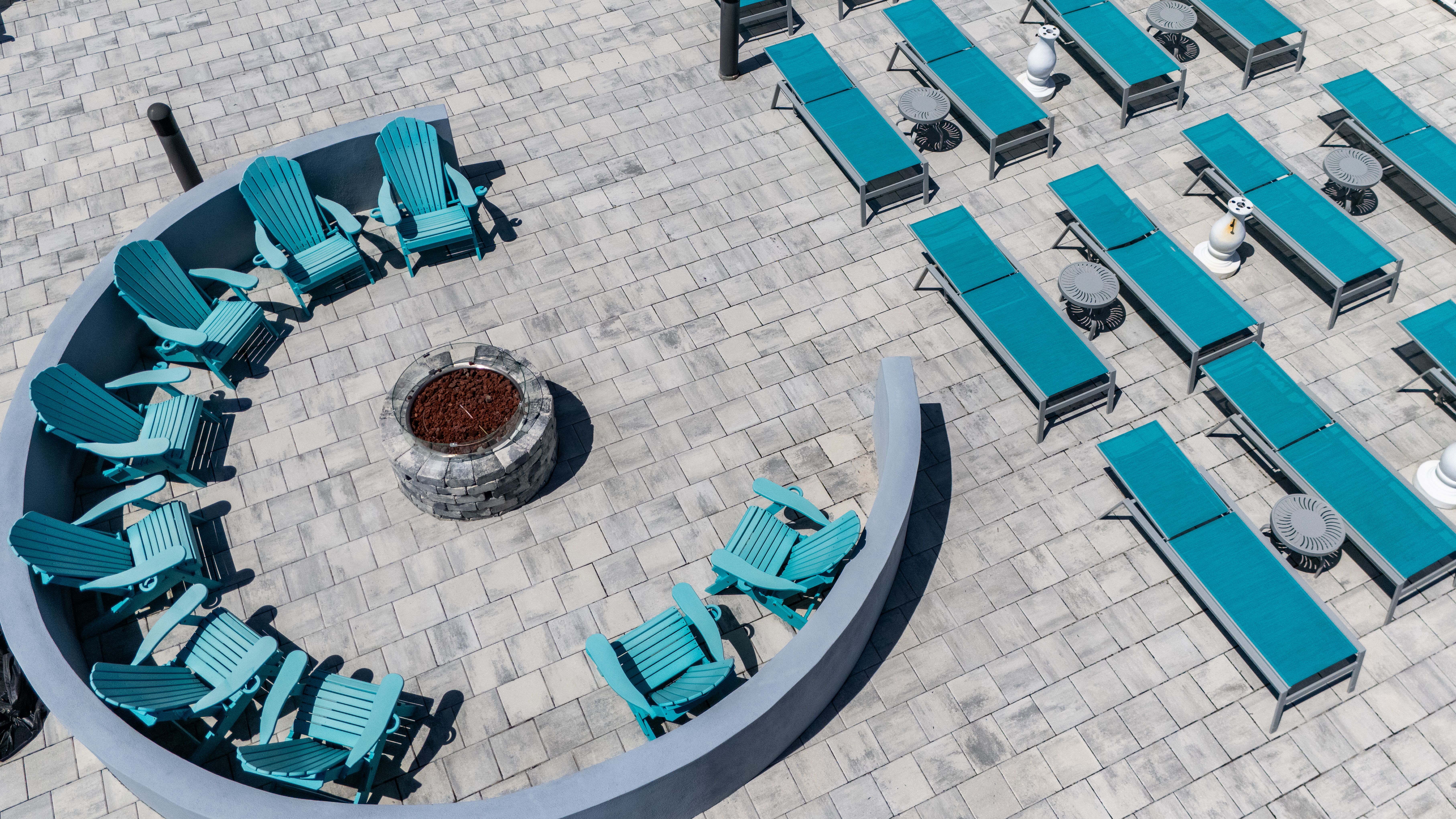 image From above, an inviting circle of teal chairs encircles a fire pit, complemented by rows of lounge chairs, creating a perfect gathering space for sunbathing or stargazing.