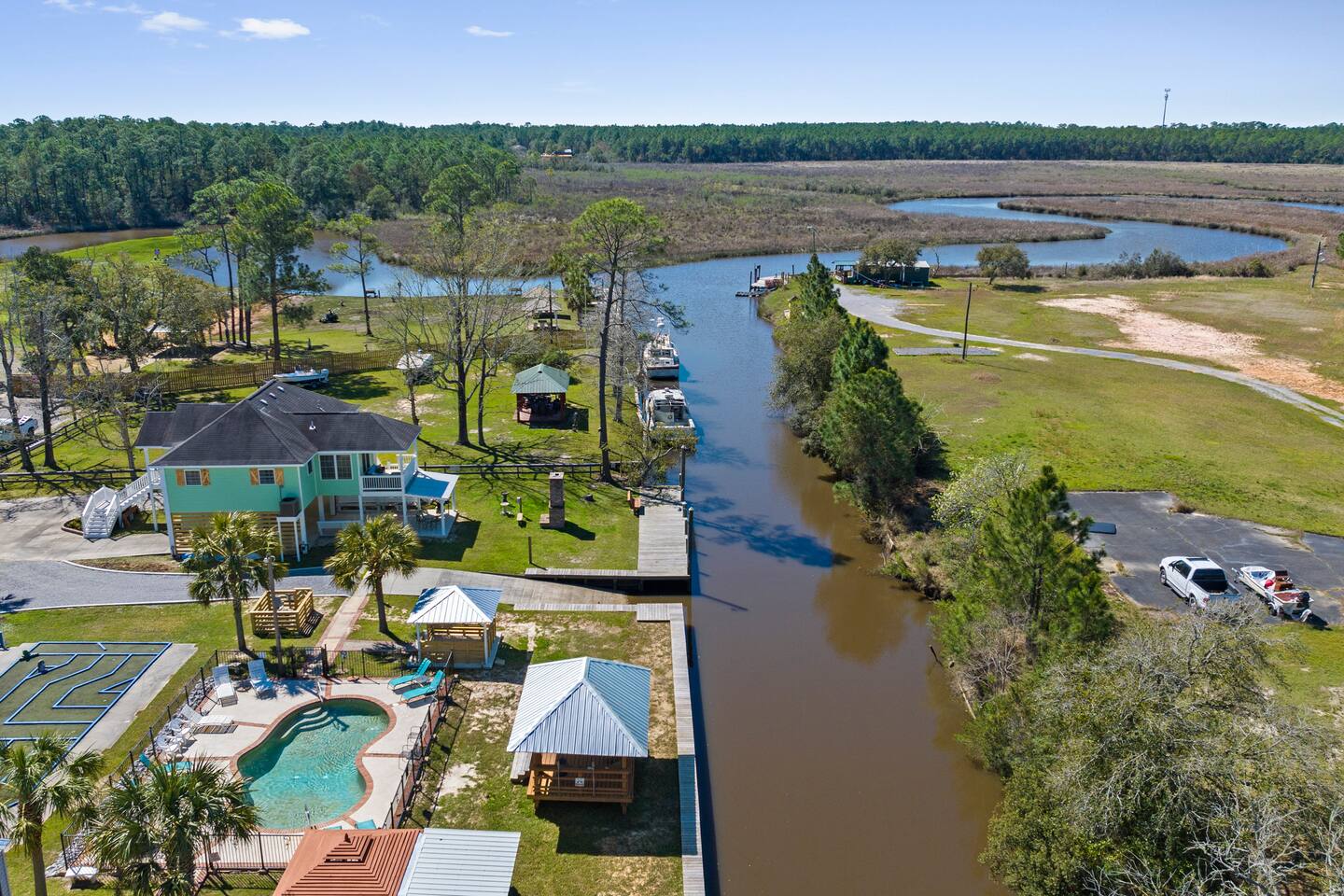 image Aerial view of the waterfront home showcasing its inviting pool, spacious deck, and surrounding lush greenery.