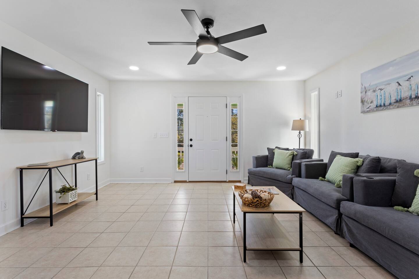 image The cozy living room features comfortable seating, a large TV, and plenty of natural light pouring in from the windows.