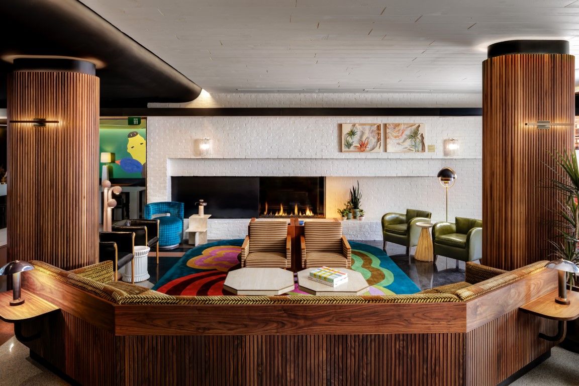 image A cozy lounge area in The Drake Hotel highlights its art-forward design with a stunning fireplace, surrounded by bold colors and unique seating.