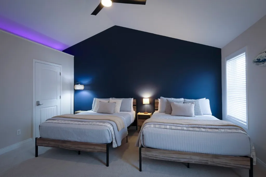 image Boasting a modern aesthetic, this well-appointed bedroom features two stylish beds set against a striking navy wall, creating an inviting space for restful nights surrounded by family comfort.
