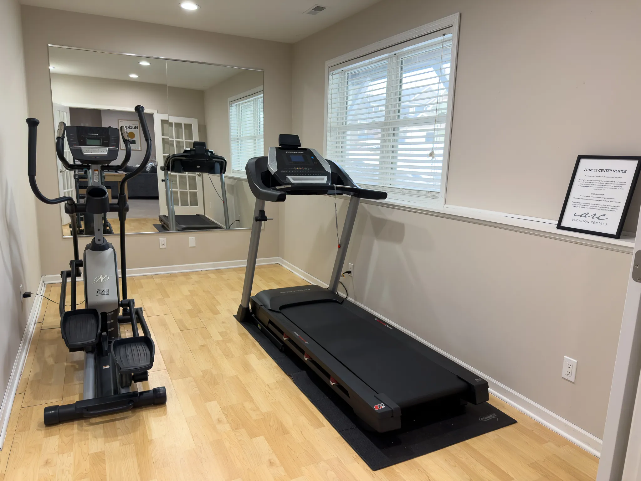 image A mirror enhances this multipurpose fitness room, featuring state-of-the-art equipment, providing a motivating environment for workouts with ample natural light.