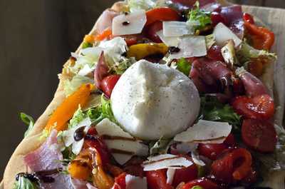A mouthwatering flatbread loaded with fresh vegetables and creamy burrata, a delightful treat for guests at the resort.