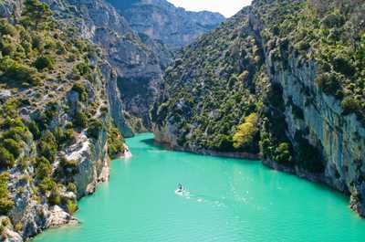 The tranquil turquoise waters of the river wind through dramatic cliffs, inviting adventurers to explore its hidden gems.