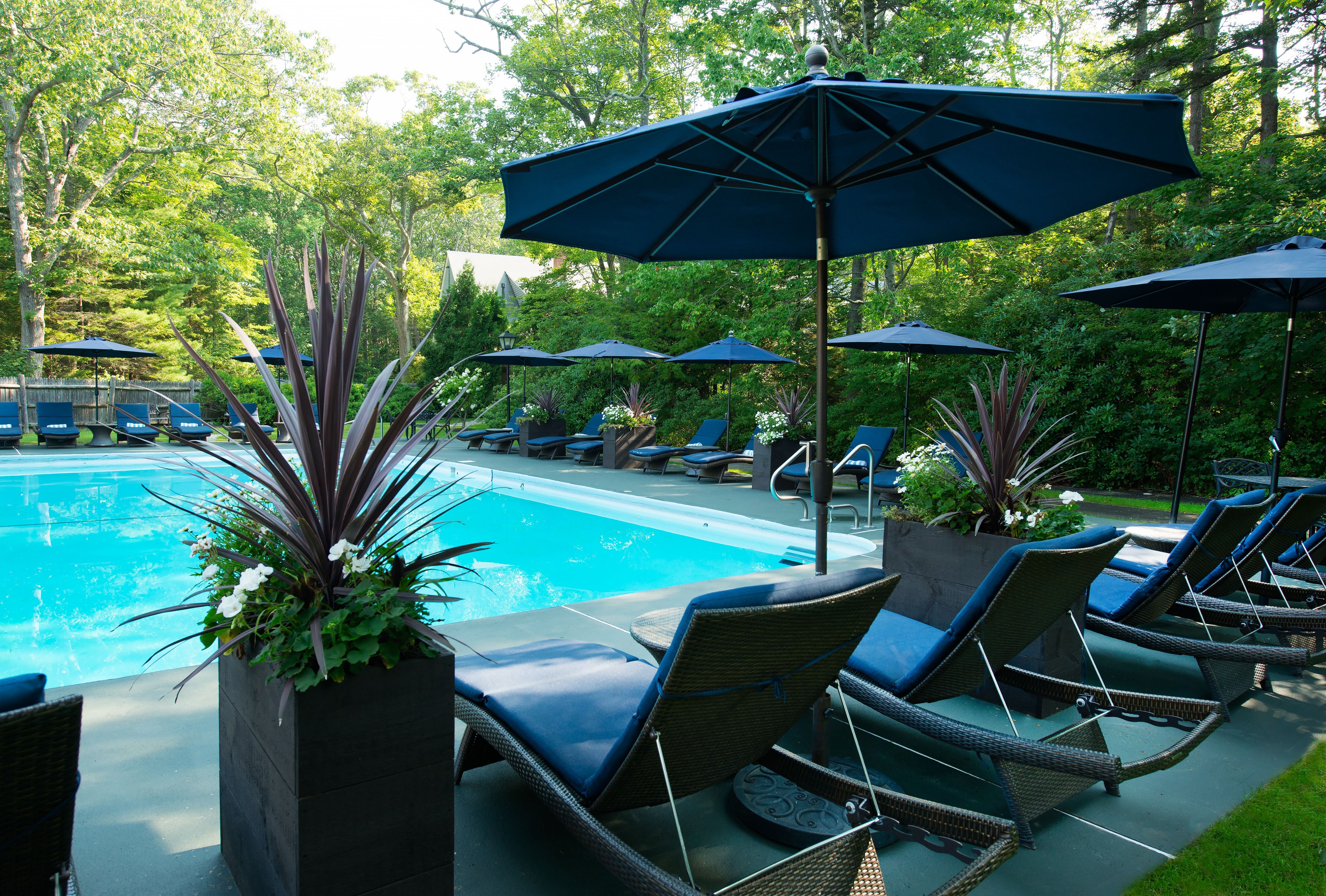 image A tranquil poolside scene adorned with stylish umbrellas and comfortable lounge chairs, perfect for soaking up the sun at this coastal retreat.