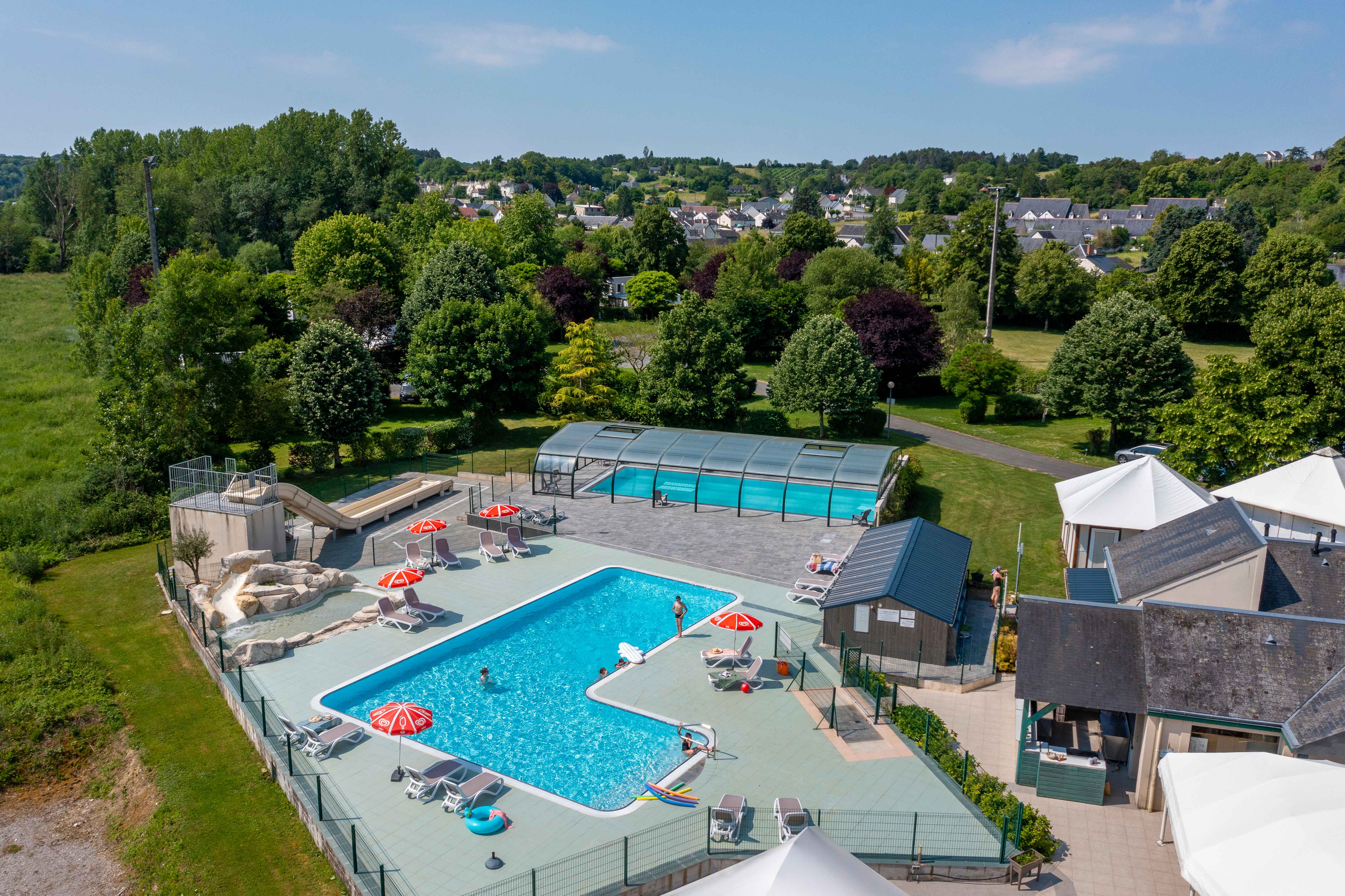 image Dive into relaxation at Camping La Citadelle, where the sunlit pool beckons for a refreshing dip amidst lush greenery.