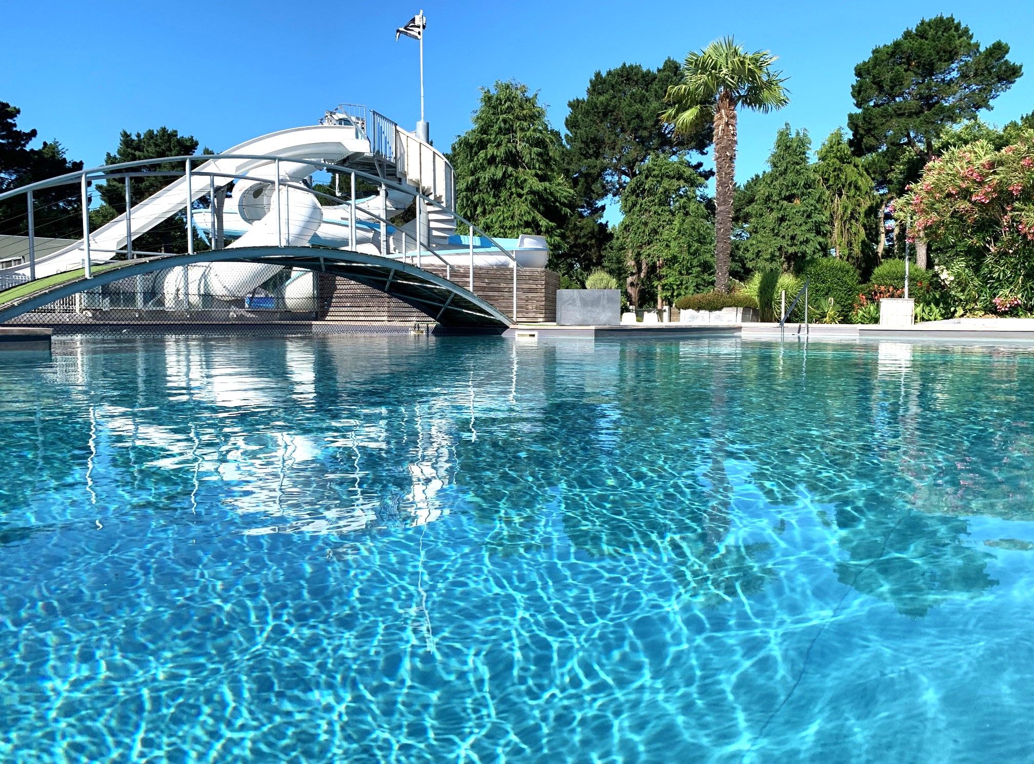 image The tranquil surface of the swimming pool reflects the clear skies, inviting guests to slide down into its refreshing waters.
