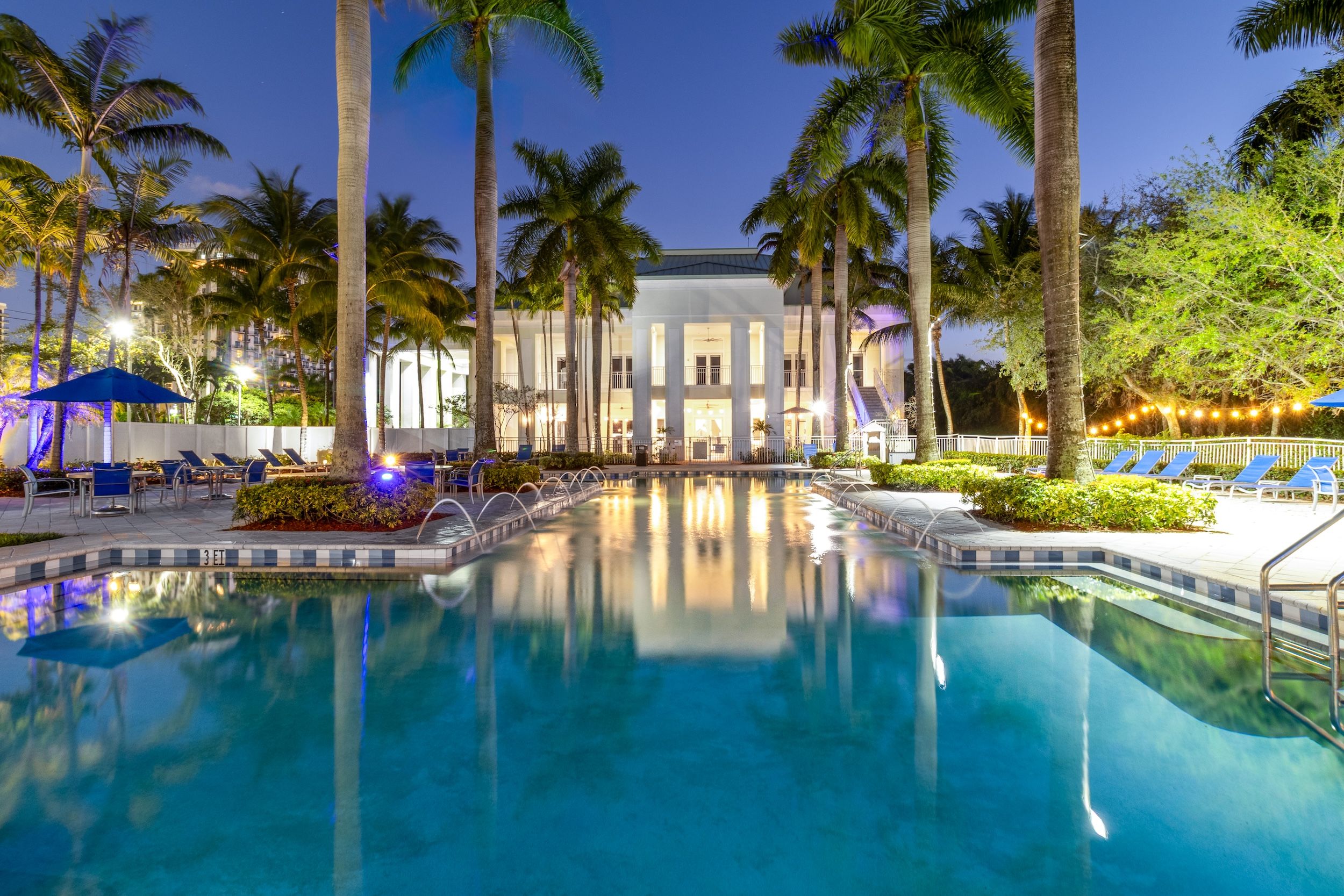 image Relax in a stunning palm-lined resort pool, beautifully illuminated at night for a true tropical escape.