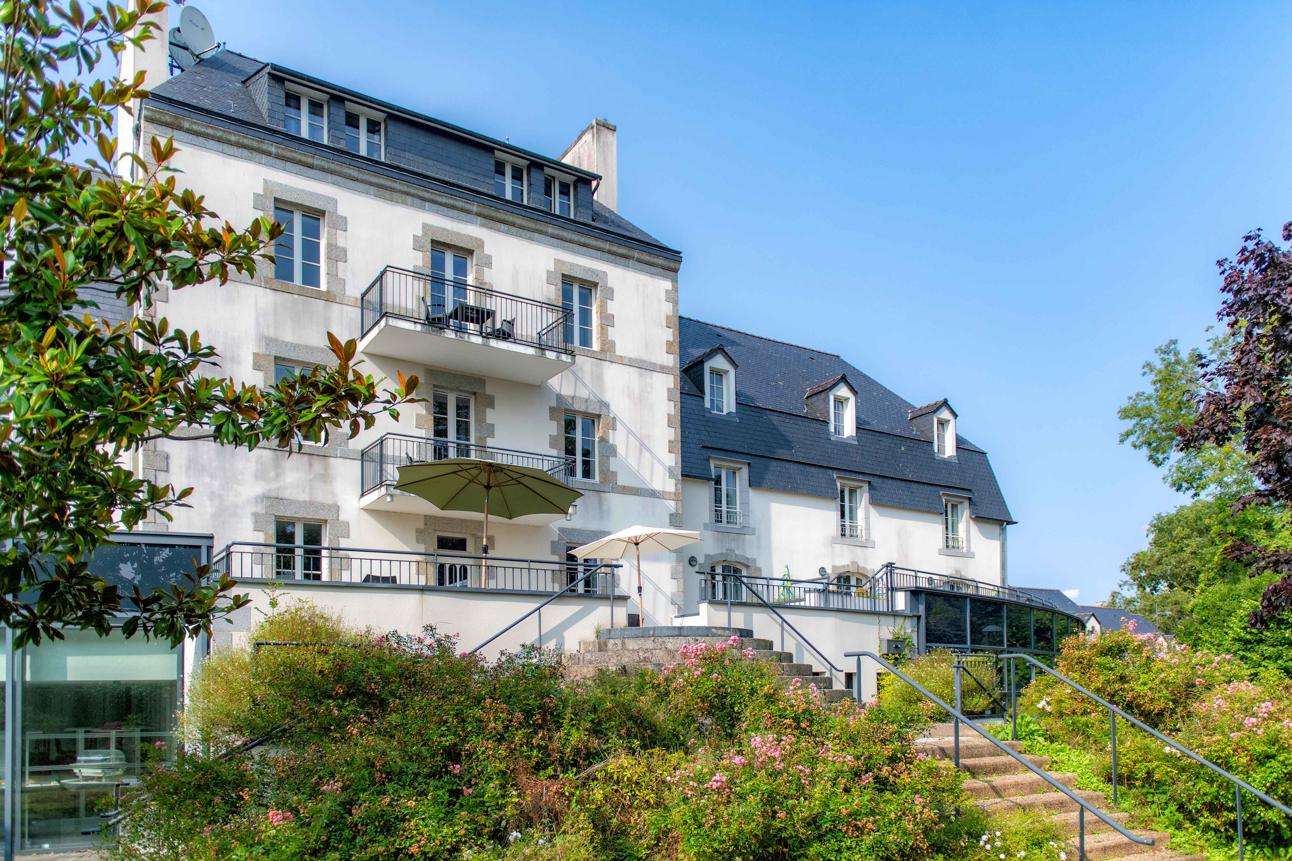 image The stone-and-render façade of Le Manoir rises above a manicured garden — your home base a short walk from Pont-Aven's galleries.