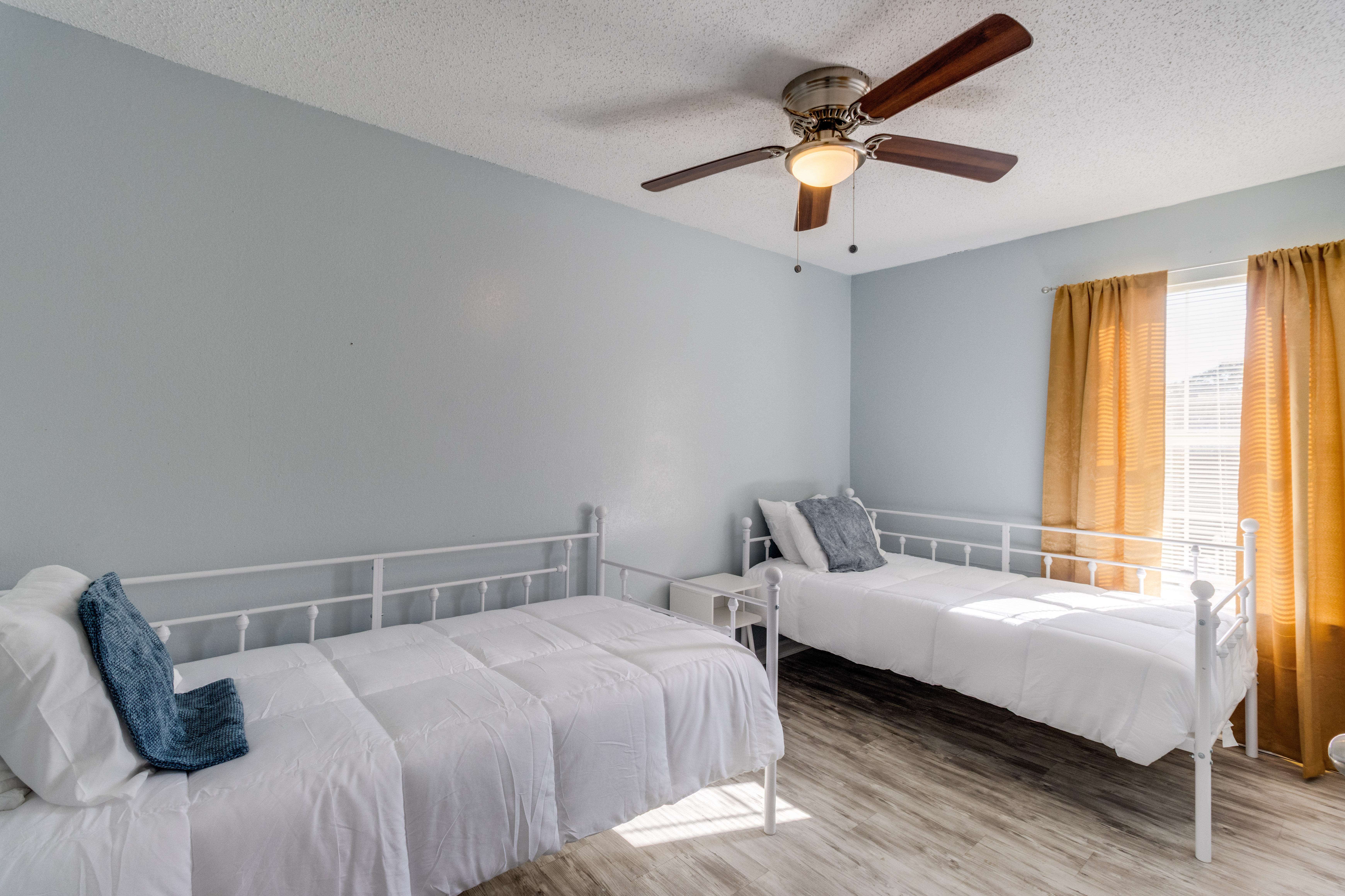 image A serene bedroom awaits with twin beds and sun-kissed curtains for a restful night's sleep.