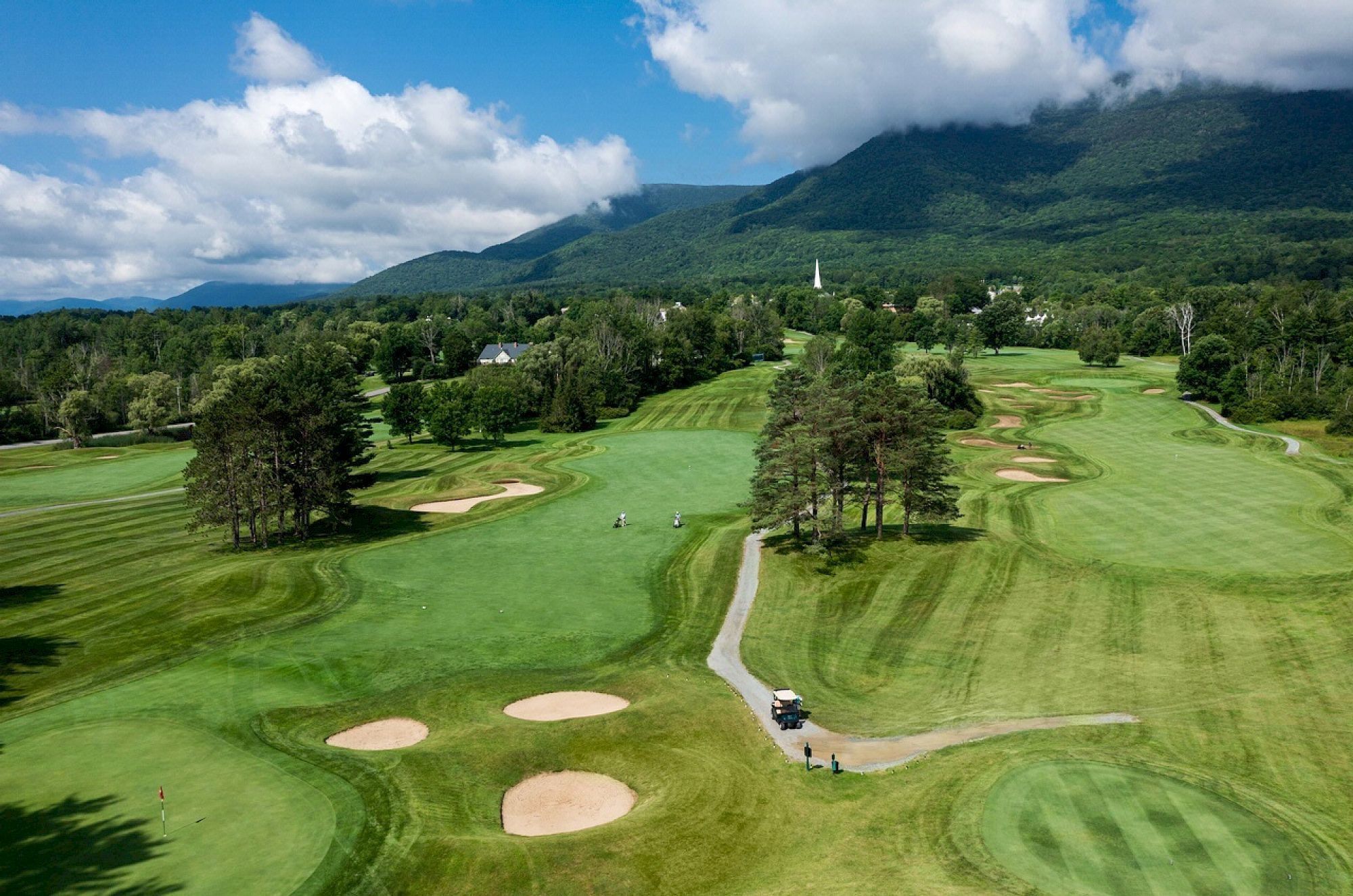 image Experience a sunny day on the lush green golf course, where rolling hills meet the sky.