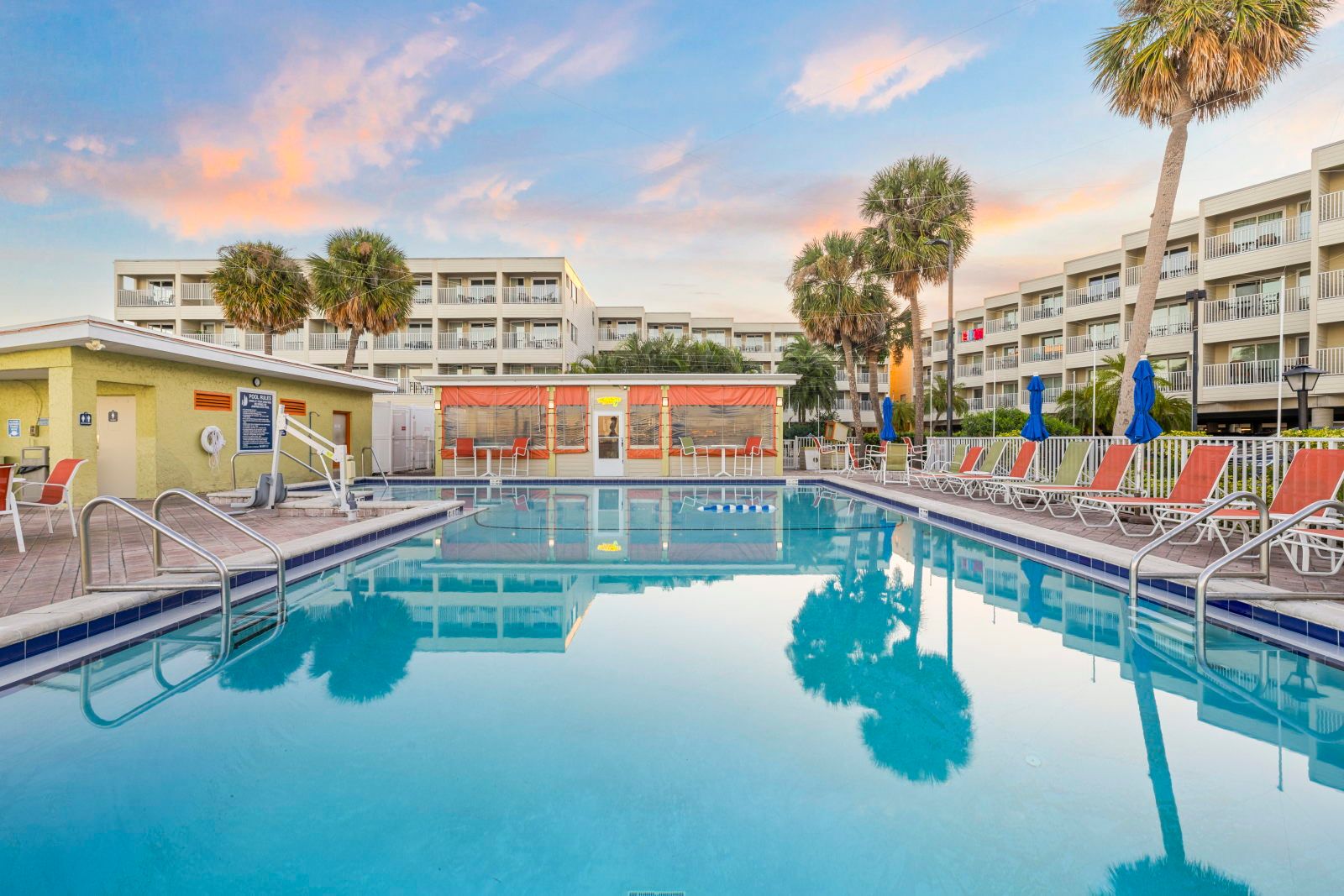 image Take a dip in the sparkling pool, framed by palm trees and vibrant lounge chairs.
