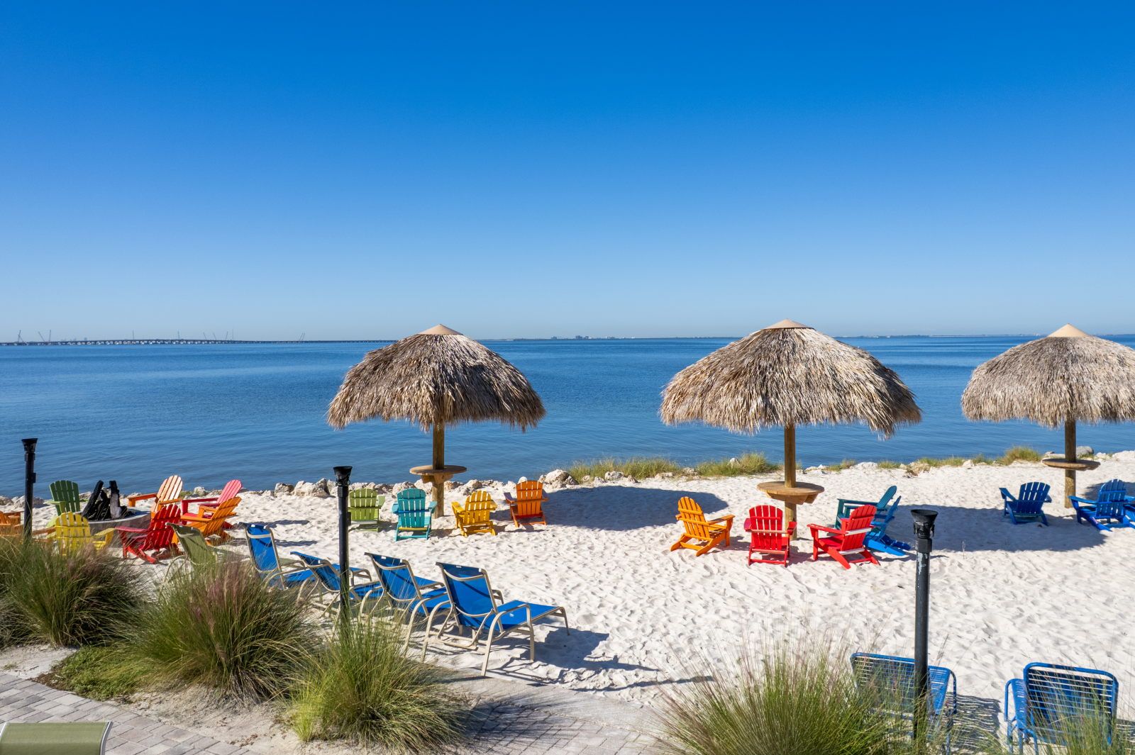 image Colorful chairs invite you to relax in the shade, mere steps from the calm waters.