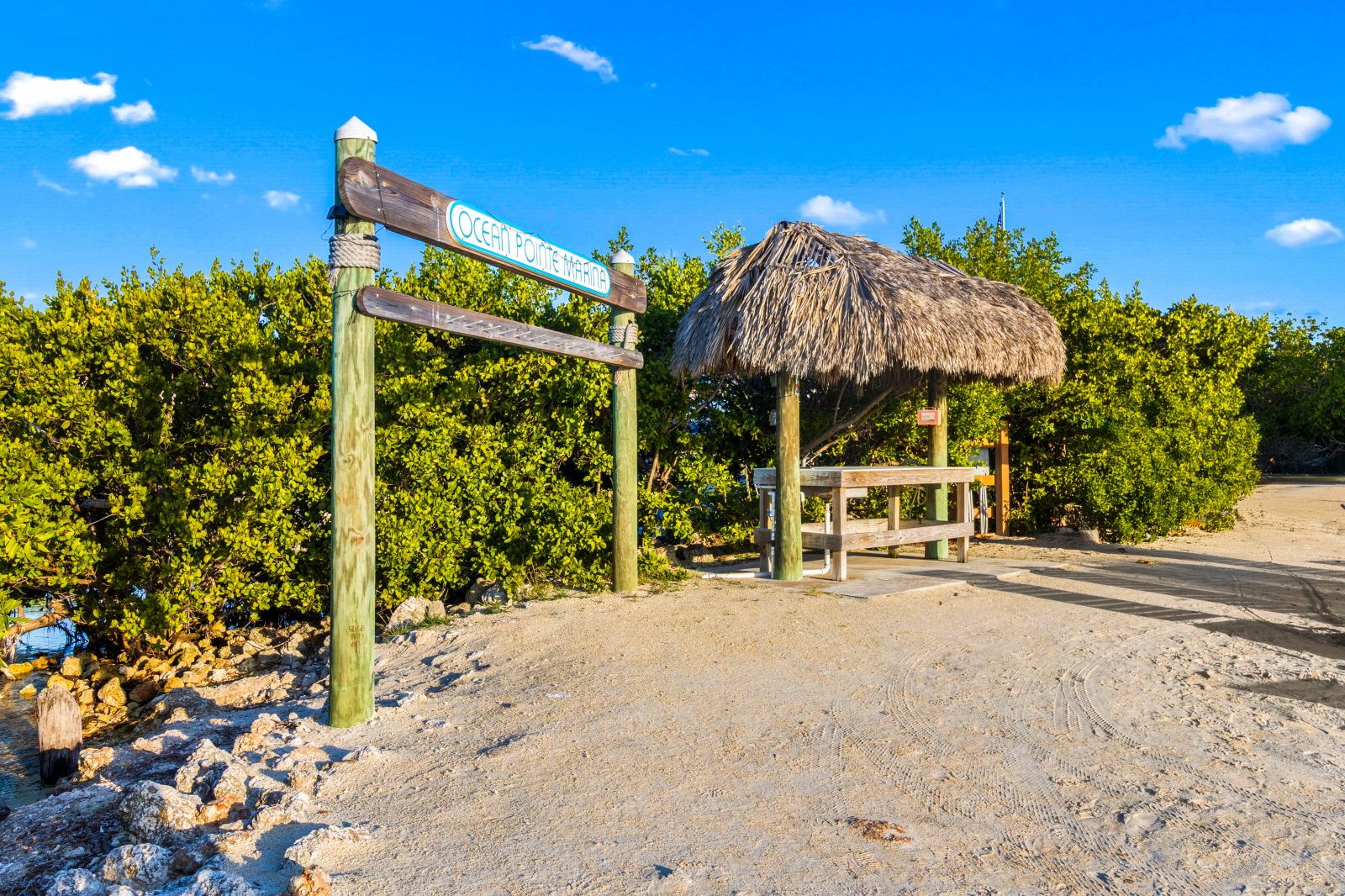 image Discover the marina entrance, a gateway to your next adventure on the water, surrounded by lush greenery and sand.