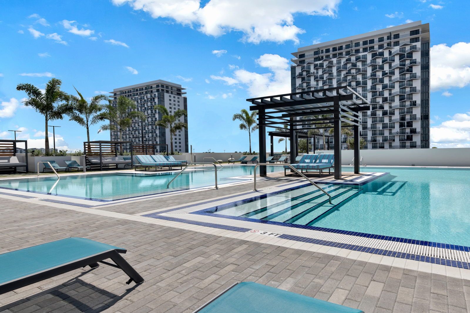 image Dive into relaxation at this stunning pool, framed by palm trees and a bright blue sky.