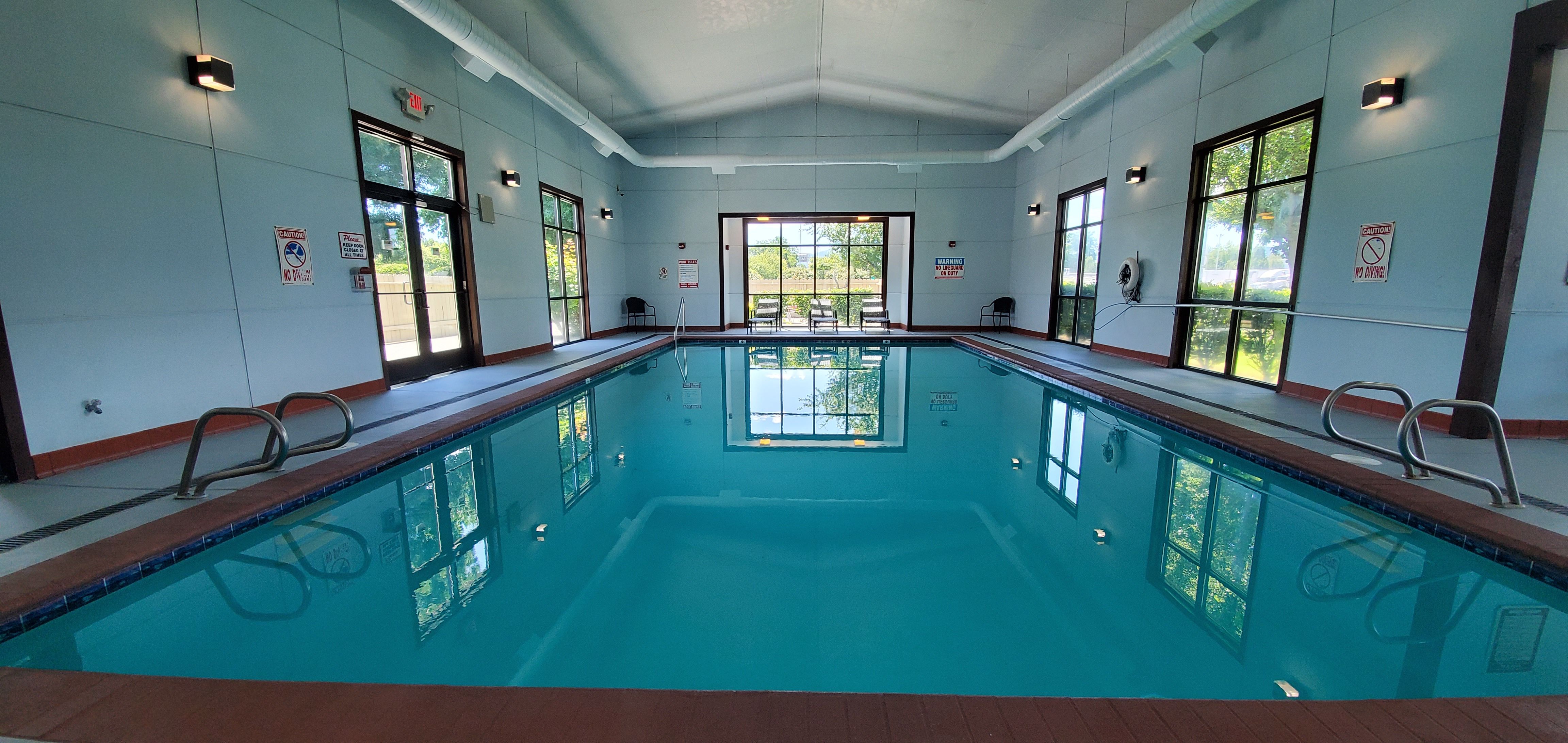 image Indoor pool and adjacent hot tub area with tile surrounds and overhead lighting.