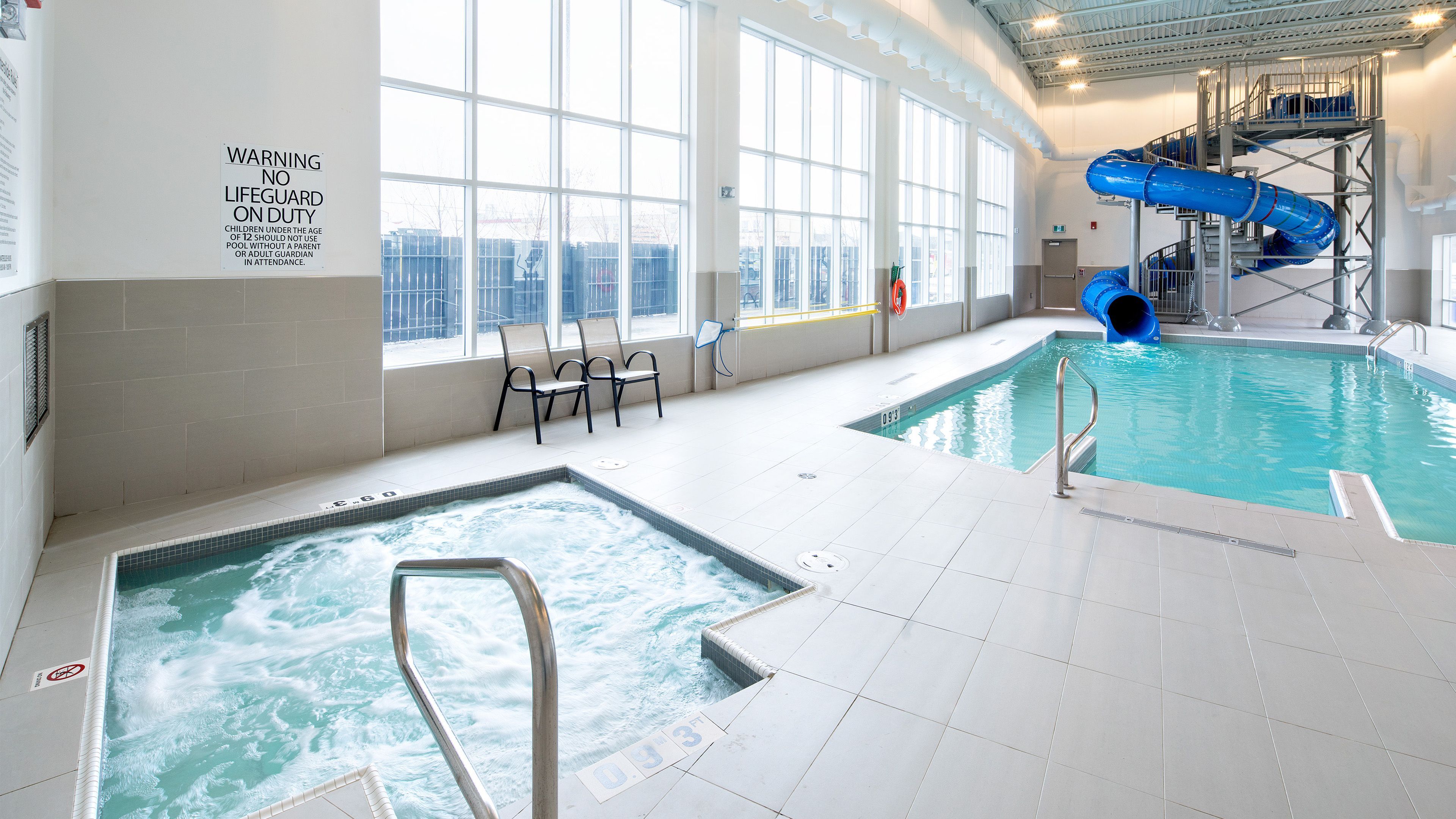 image Indoor pool featuring a hot tub and a water slide.