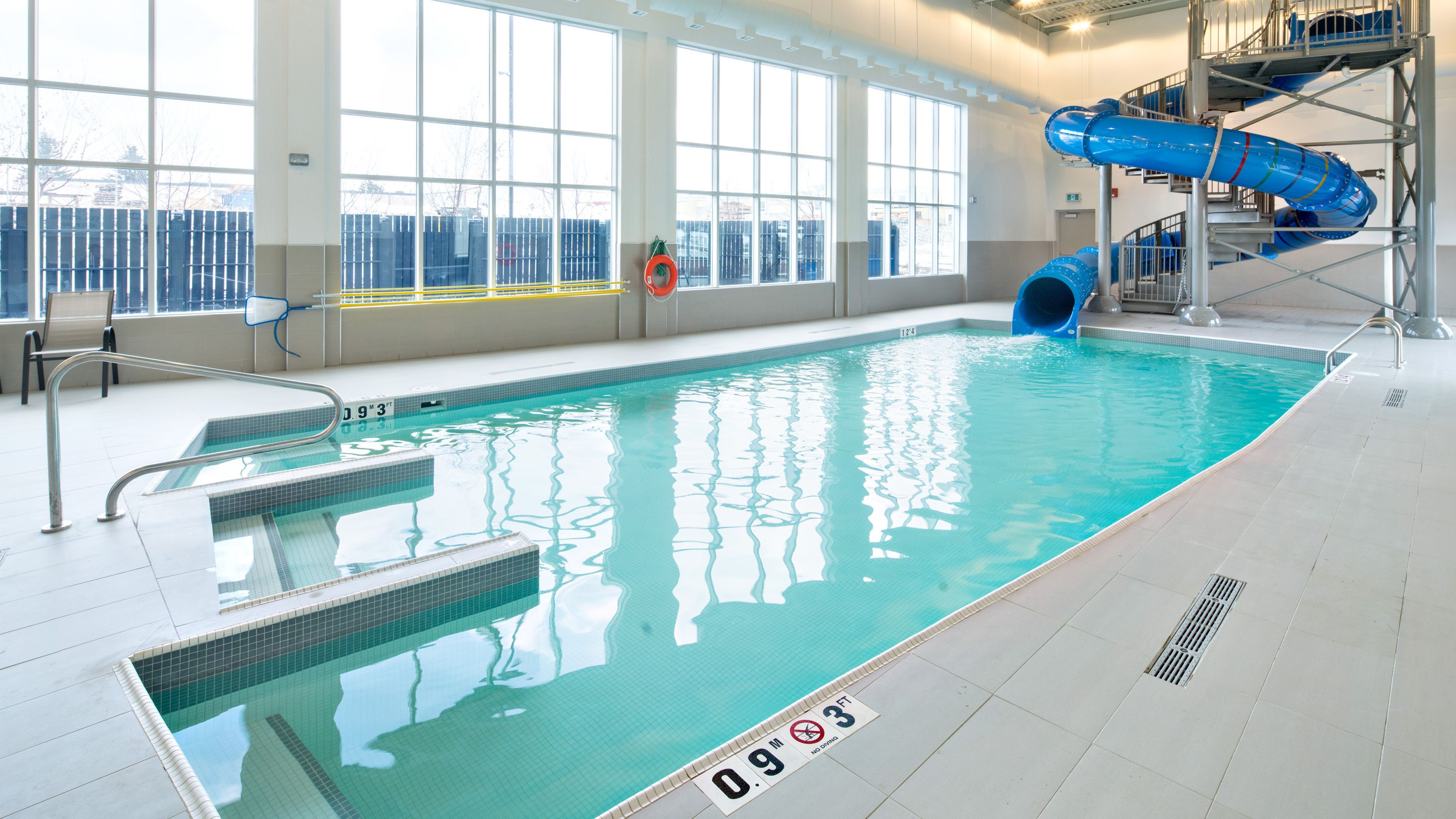 image Clear indoor pool with a well-lit and inviting water slide.