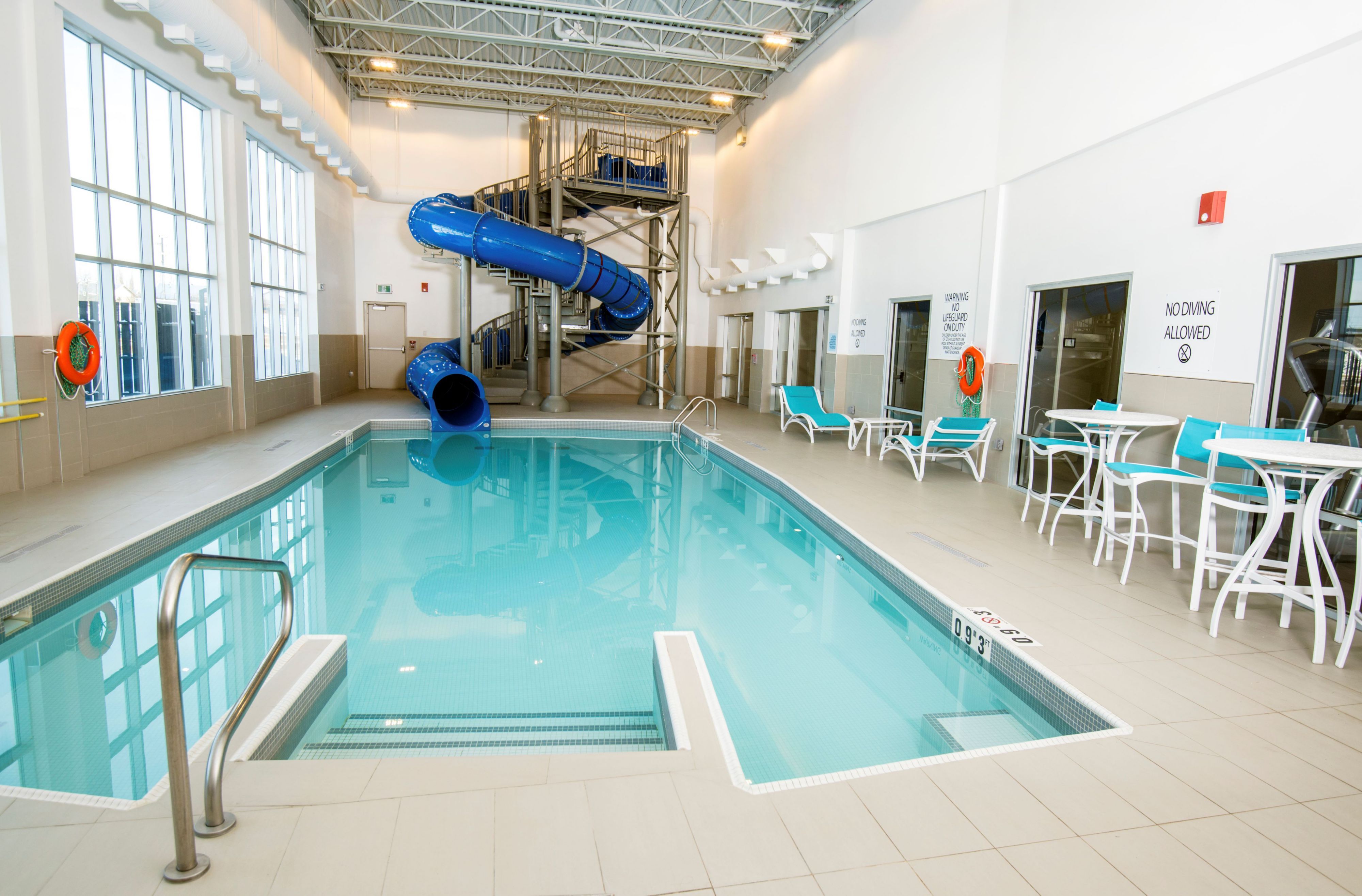 image Bright pool area with blue water slide and lounge chairs.