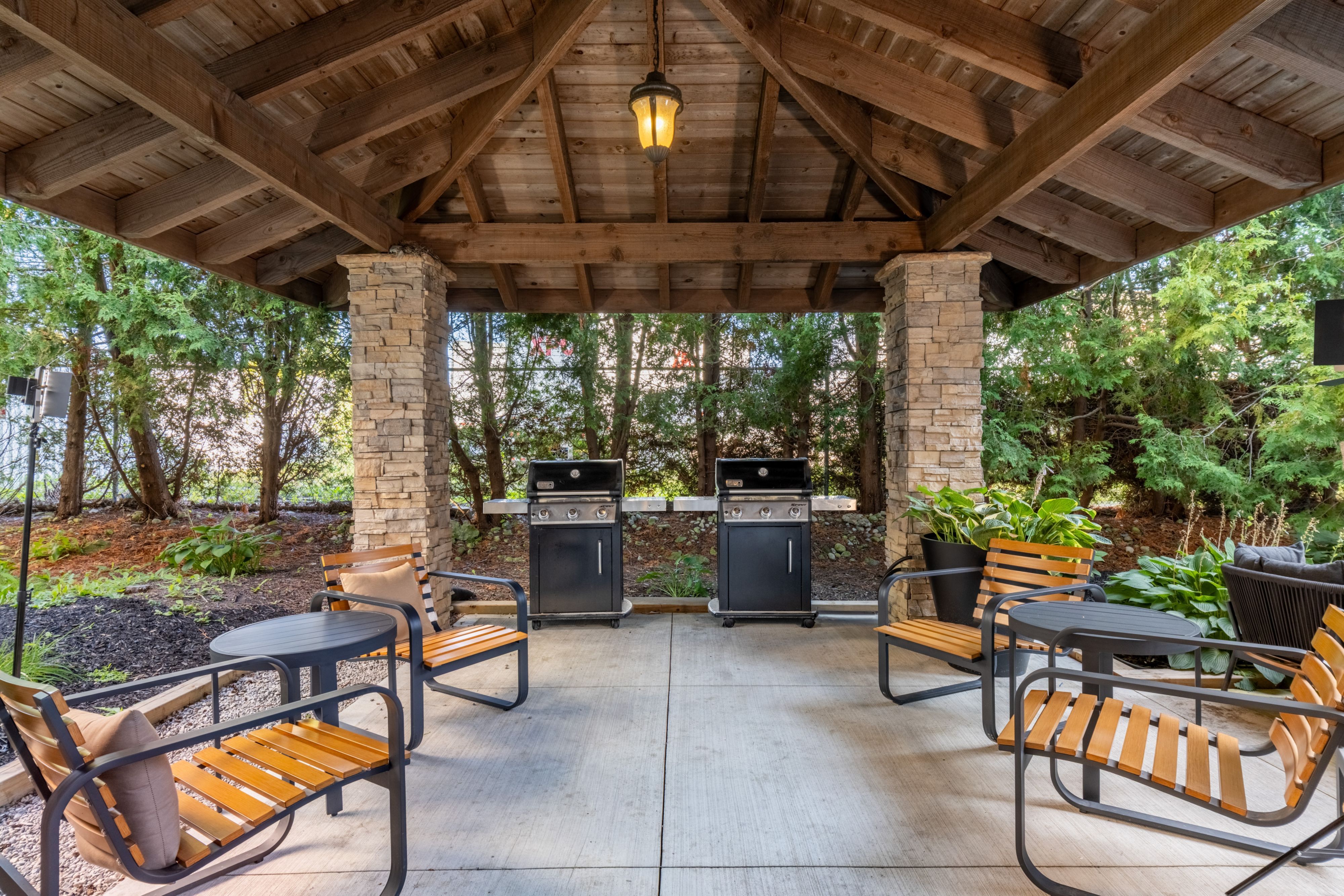 image Cozy outdoor seating area with grills and lush greenery.