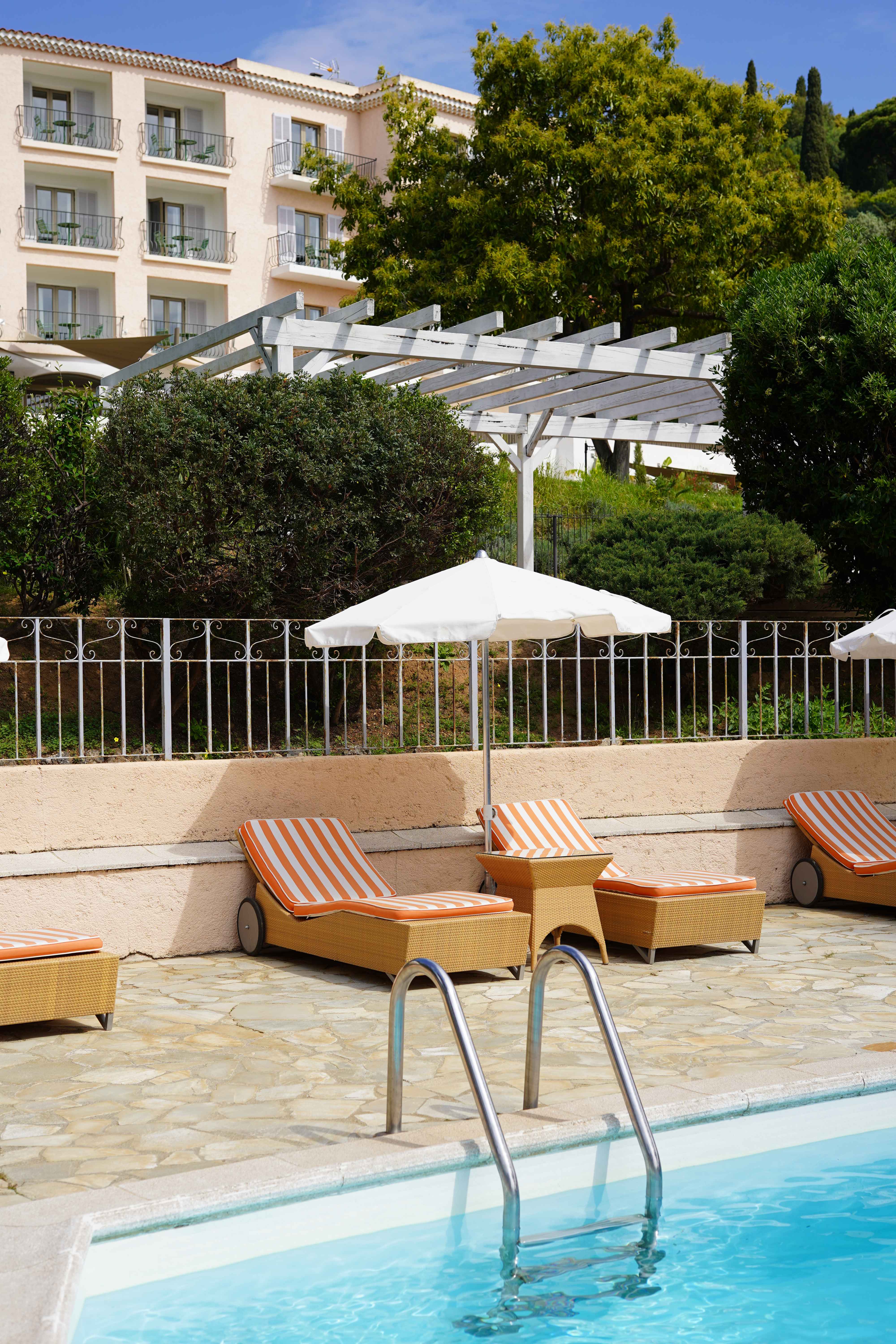 image Orange-cushioned wicker loungers line the heated pool — the beach is just a 5-minute walk from here