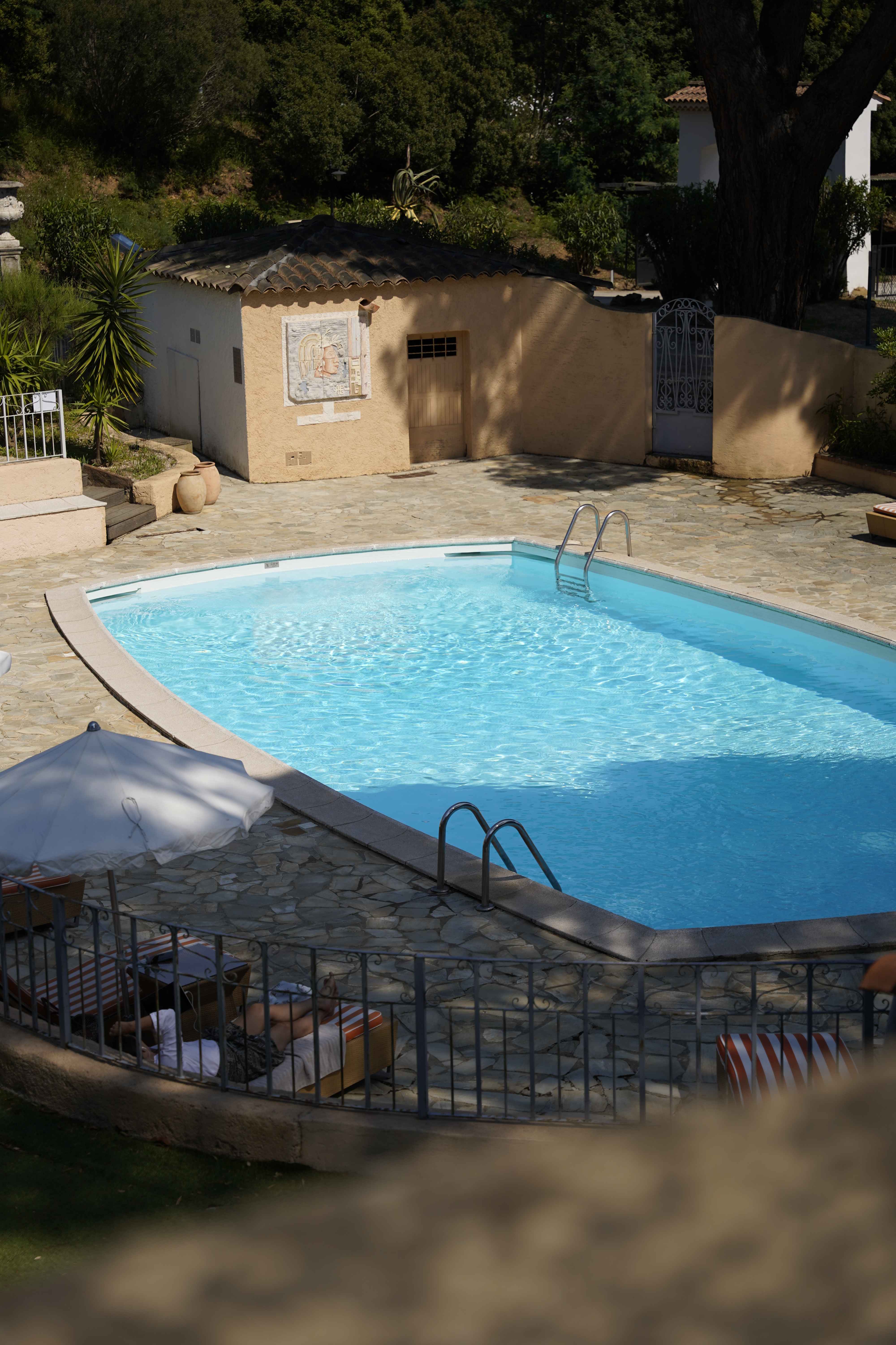 image Elevated view of the stone-paved pool terrace, sheltered on all sides by tall green hedges