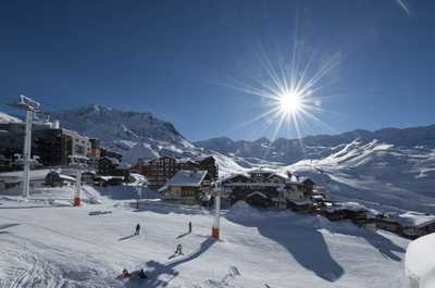 Skiers and lifts under bright winter sun in the Val Thorens area.