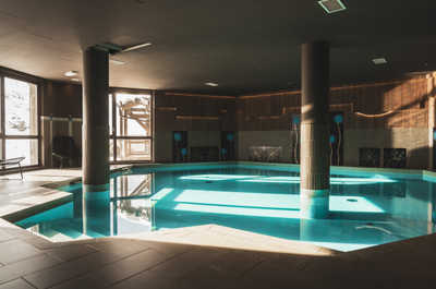 The indoor pool opens onto mountain views — jump in after a guided half-day hike with the Bureau des Guides des Belleville.