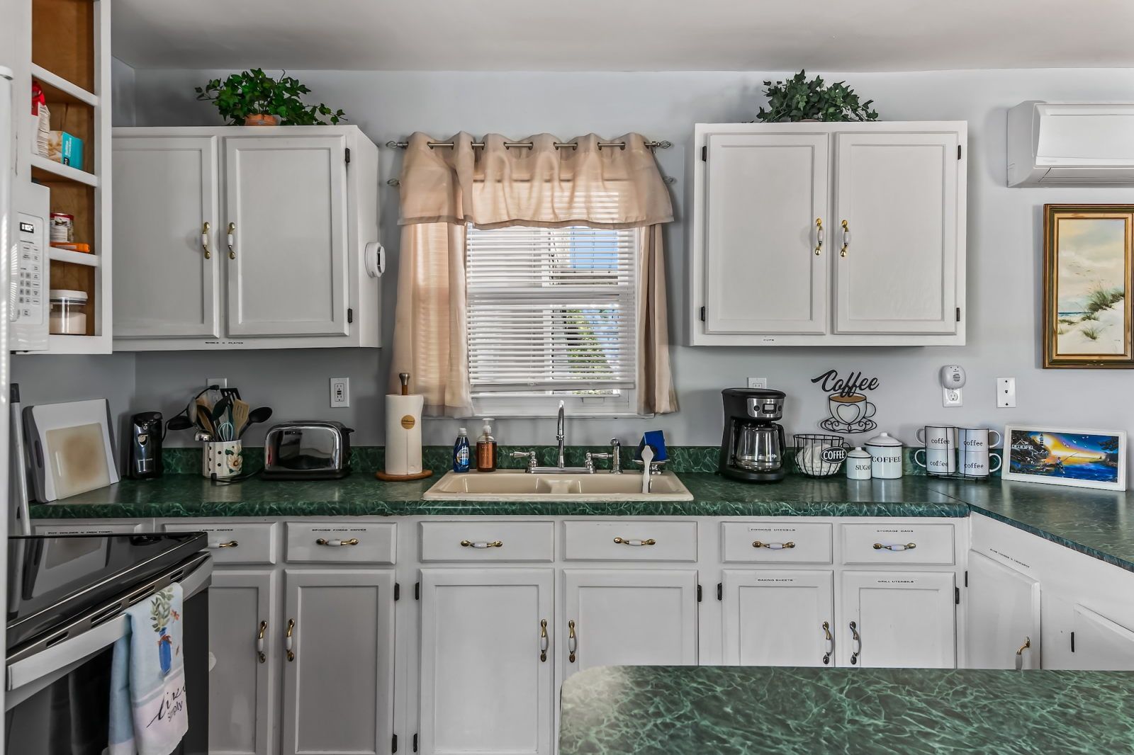 image White cabinets with gold hardware and a green countertop give the kitchen a fresh, coastal-cottage feel