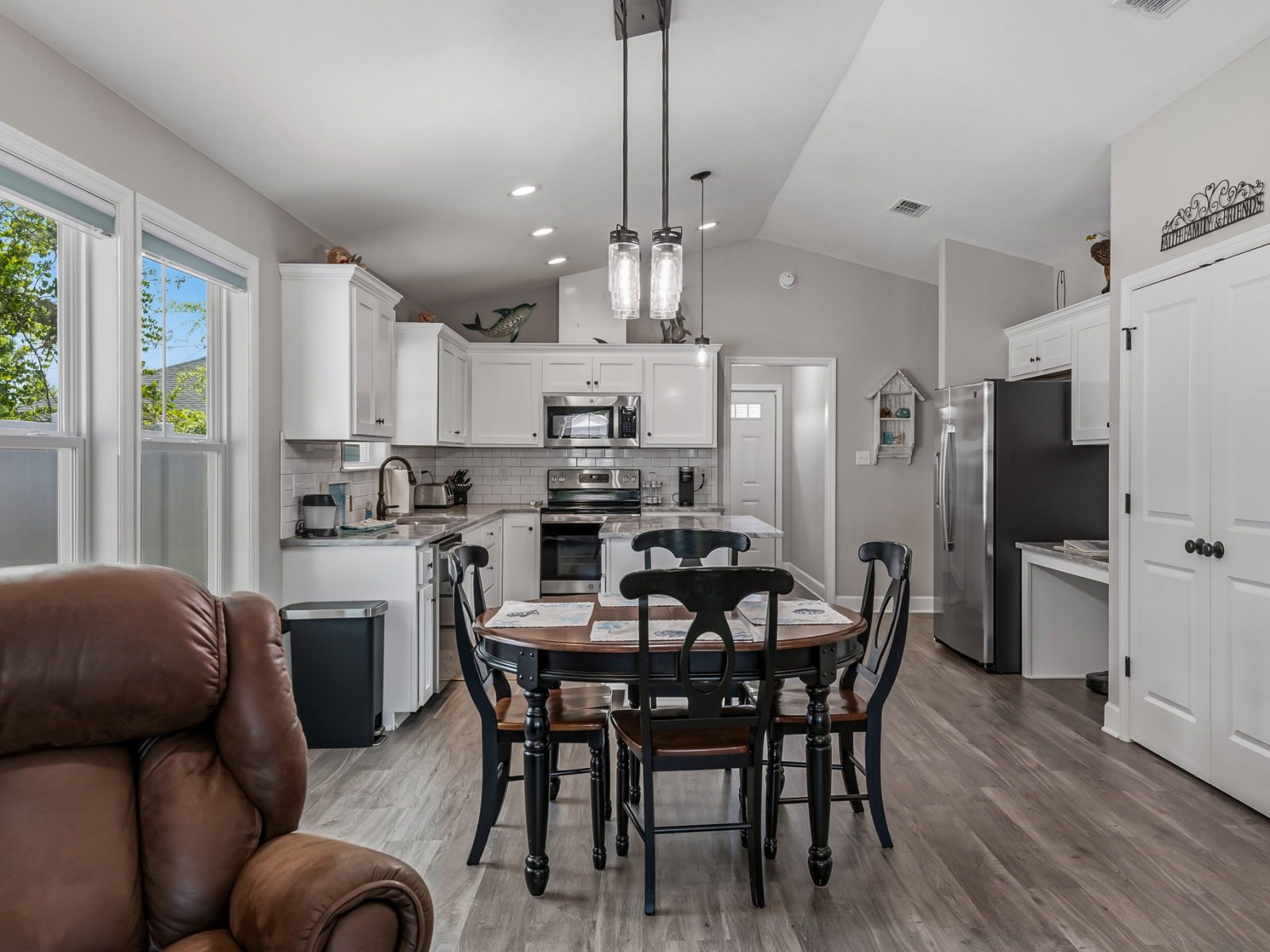 image Open-plan kitchen and dining area with black countertops, white cabinetry, and a large central island