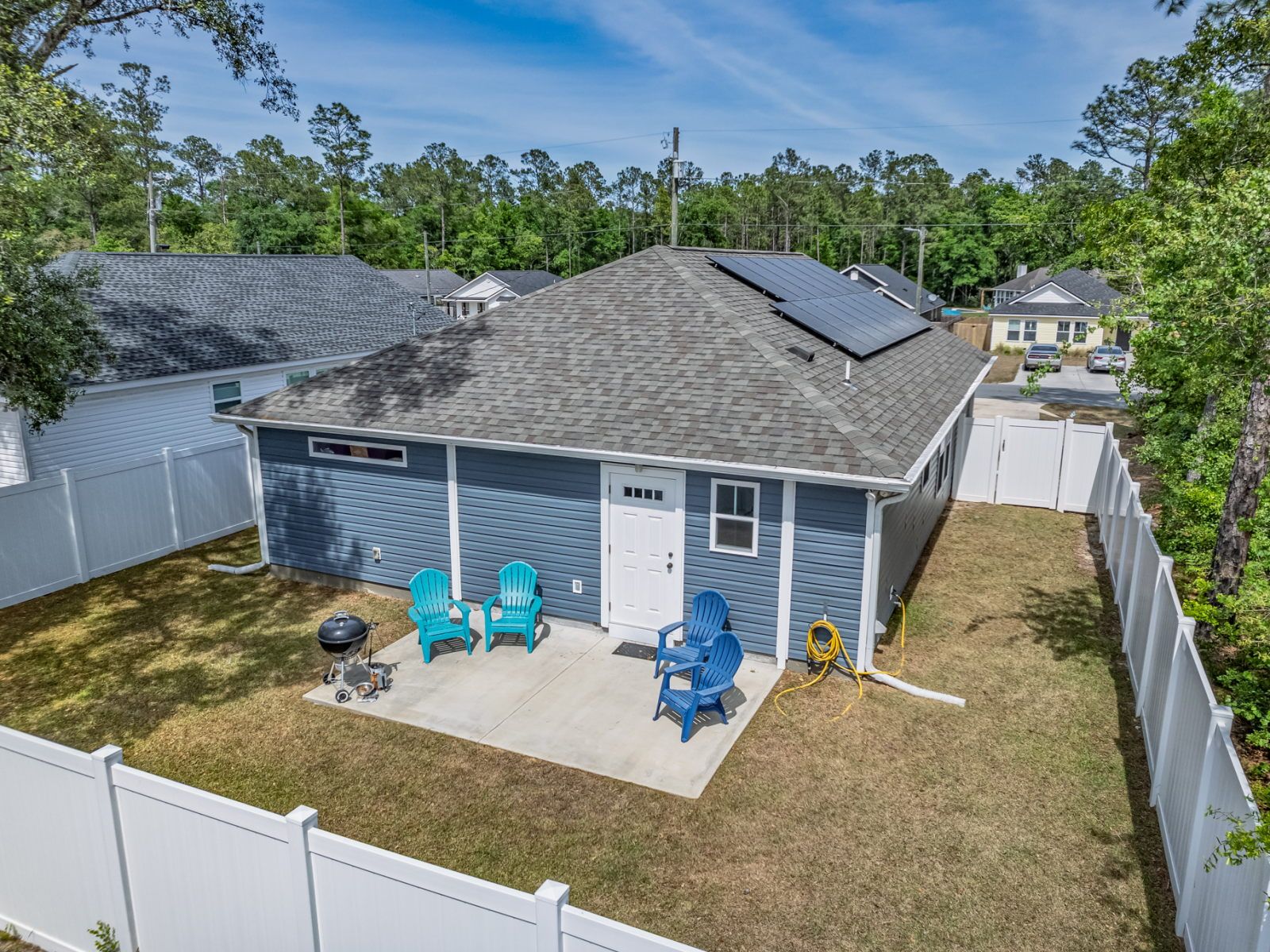 image Aerial view of the backyard — white-fenced yard with blue Adirondack chairs and BBQ patio