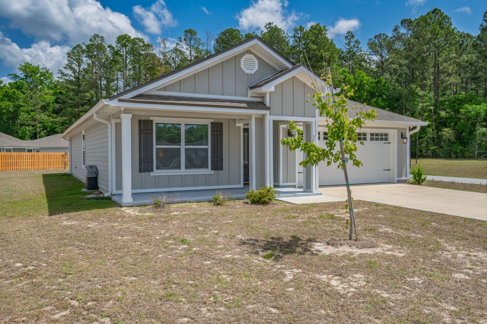 image Front exterior with white porch columns, decorative shutters flanking the windows, and a garage on the right