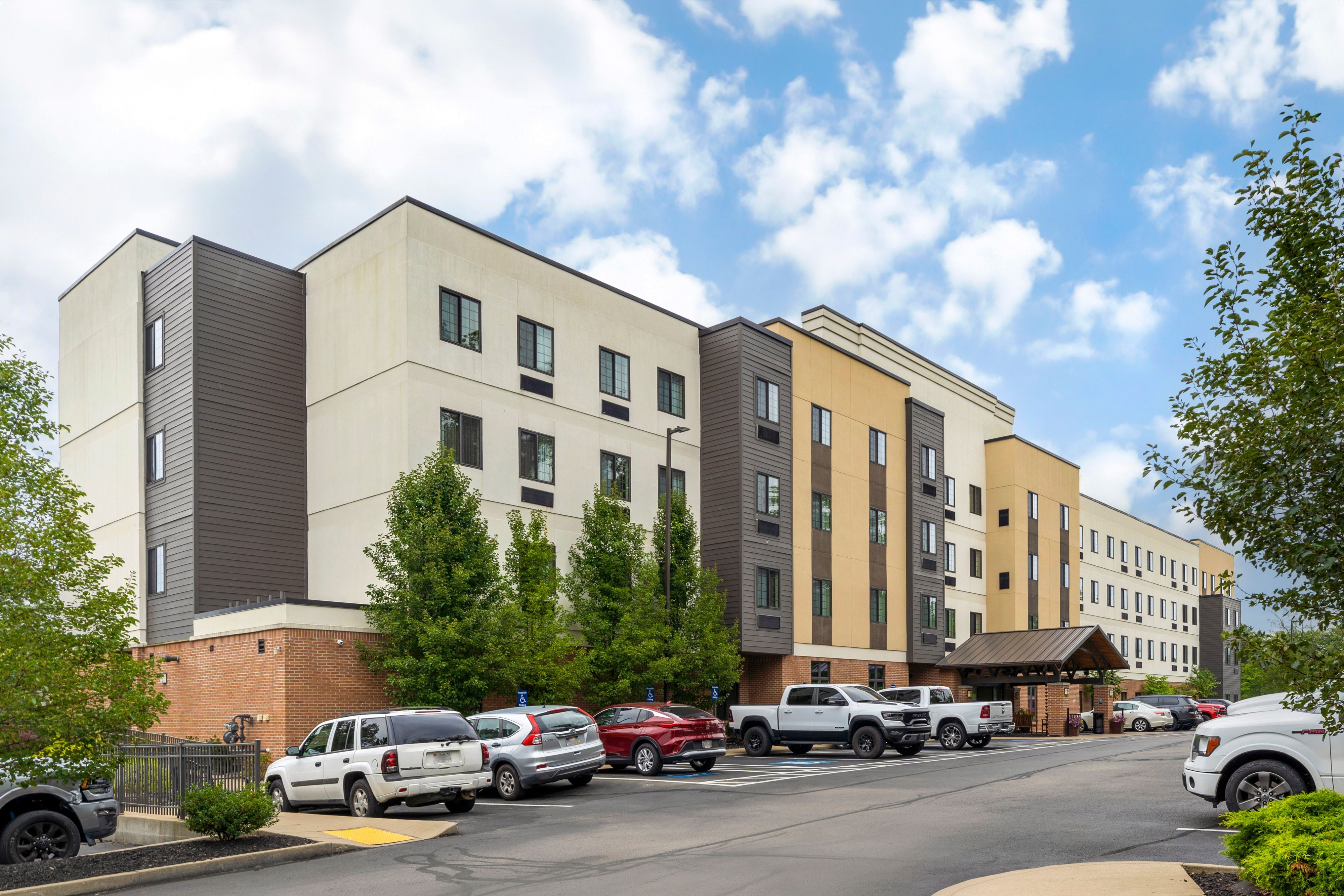 image Modern property exterior with ample parking and green surroundings.