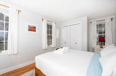 Relax in this inviting bedroom, featuring soft linens and plenty of natural light from the surrounding windows.