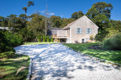 Enjoy the peaceful charm of a quaint corner lot surrounded by lush greenery and a lovely gravel driveway.