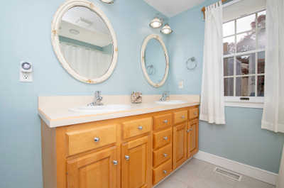 The sunlight filtering through the window illuminates a calming, blue-hued bathroom.