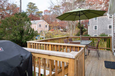 Savor al fresco dining on the deck under the shade of the umbrella, surrounded by vibrant autumn colors.