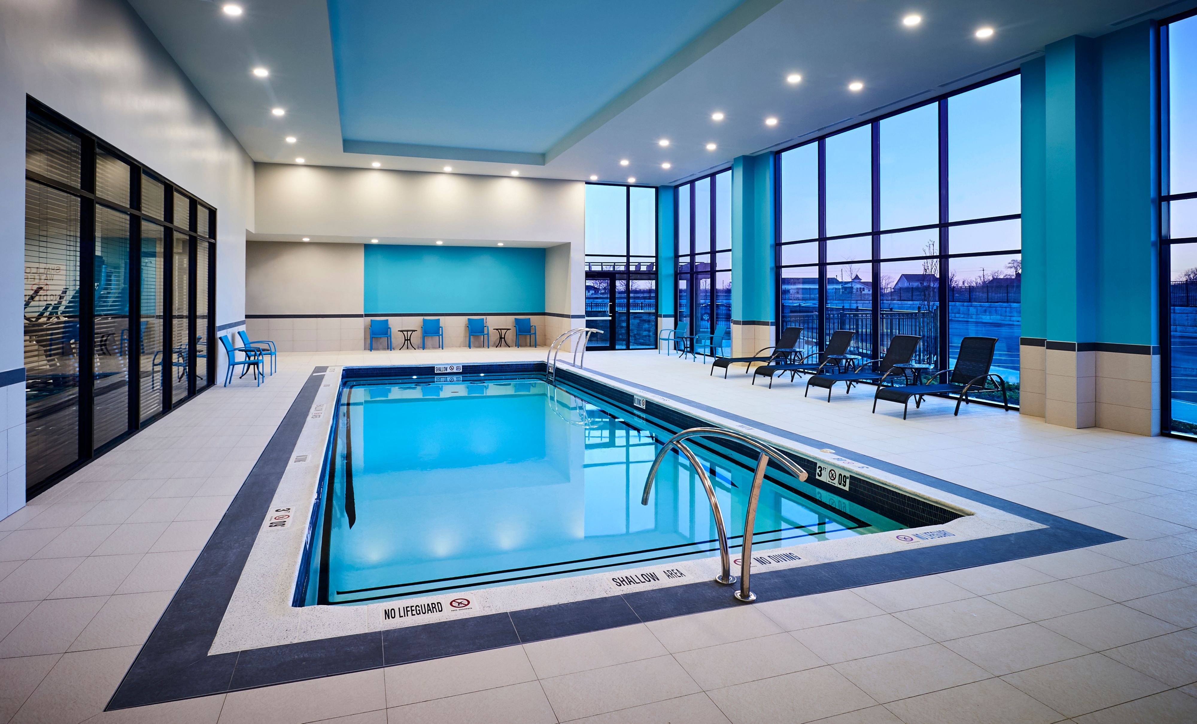 image Indoor pool with blue walls and lounge chairs.