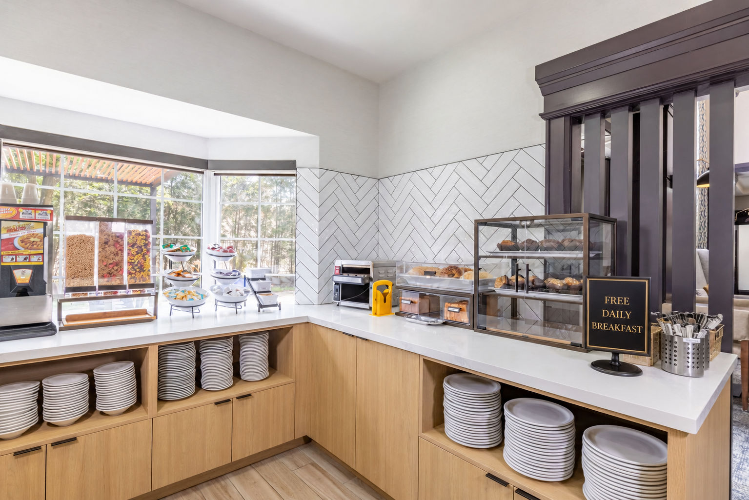 image Breakfast station with pastries, cereals, display case, and stacked plates.