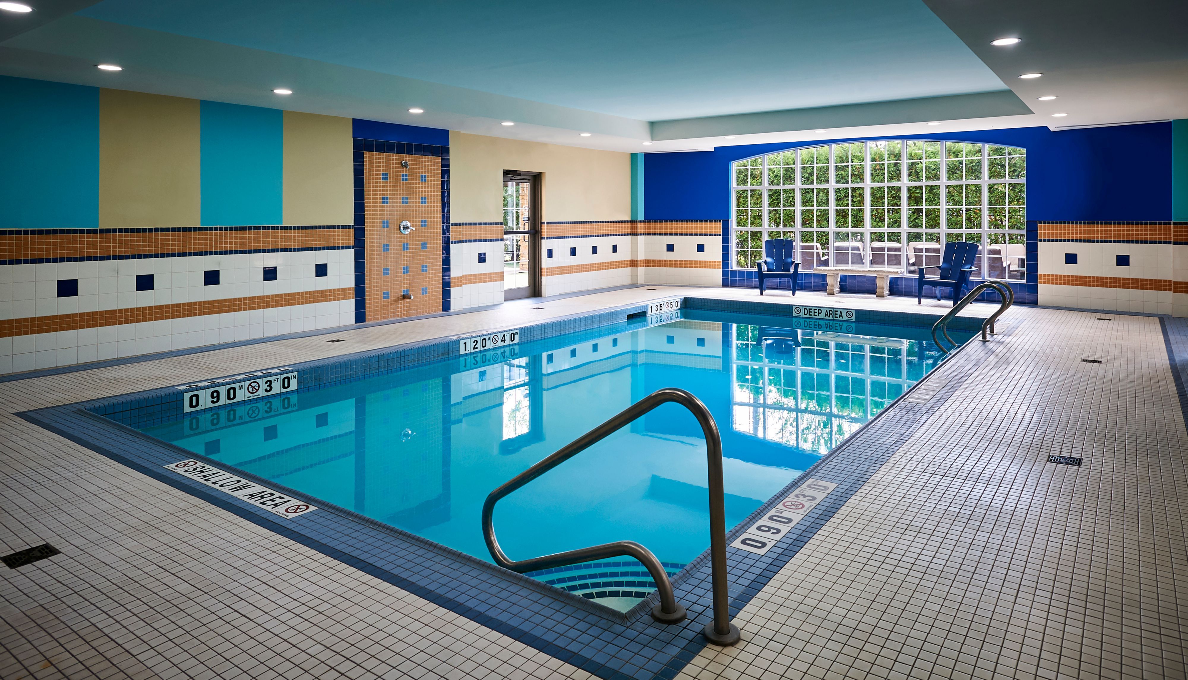 image Bright indoor pool with blue-tiled walls and comfortable seating.