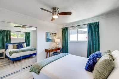 Feel at home in this cozy bedroom with vibrant green curtains and a plush bed, perfect for restful nights.