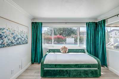 Unwind on the stylish daybed, surrounded by bright curtains and views of blooming greenery.