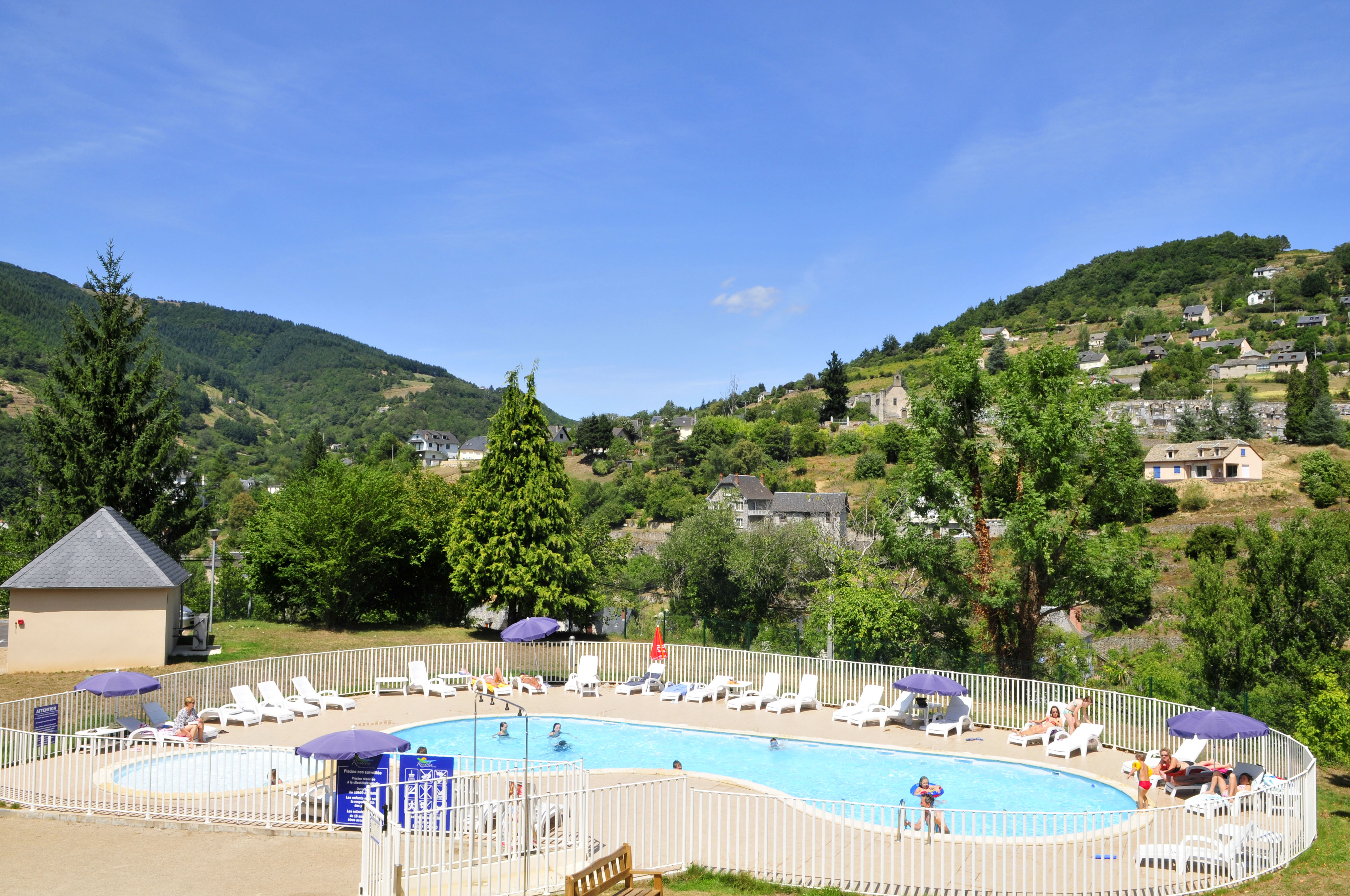 image  Outdoor heated pool with sun loungers and parasols, set against the rolling green hills of the Aveyron gorges.