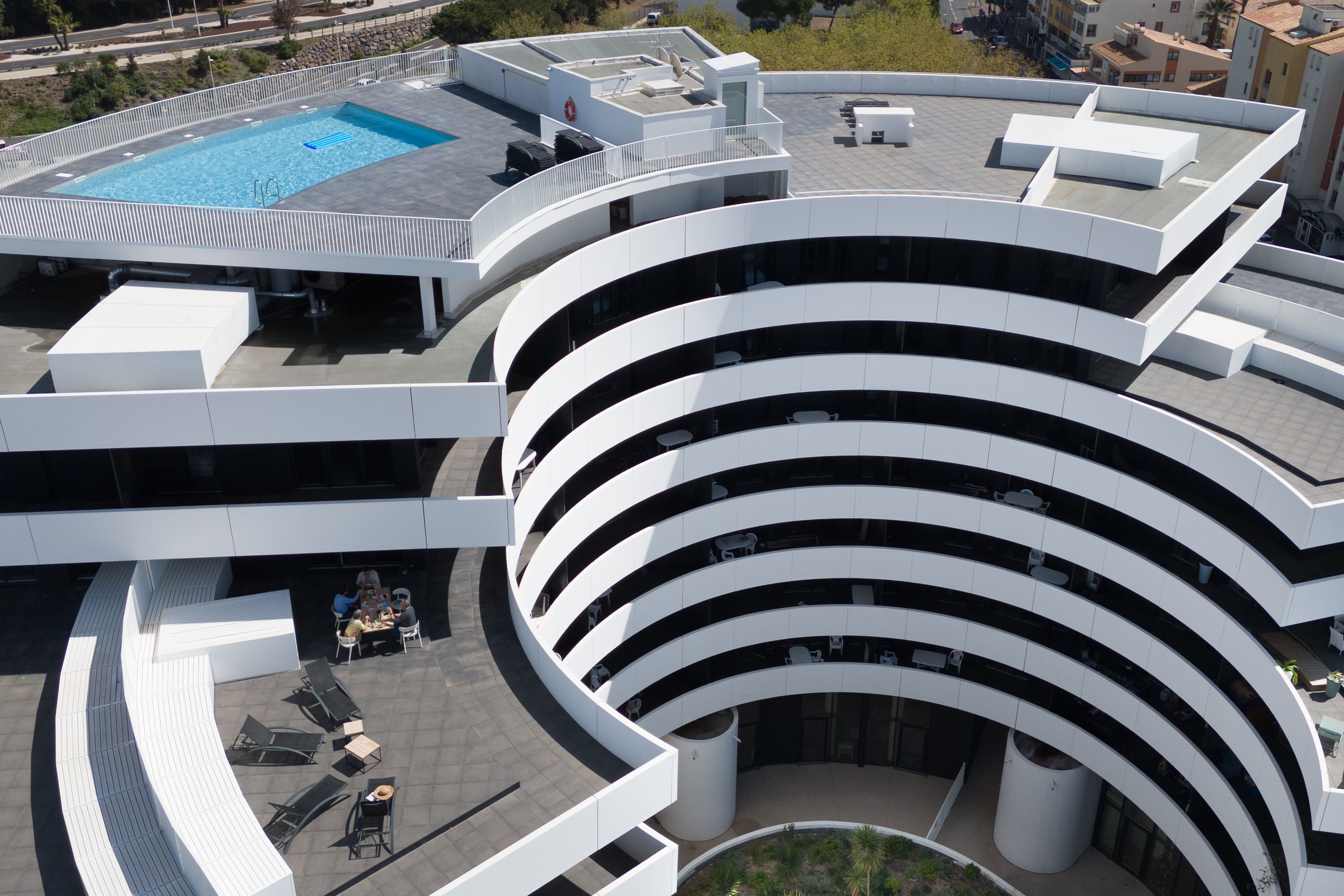 image Black lounge chairs circle the rooftop pool, set within the building's signature curved architecture.